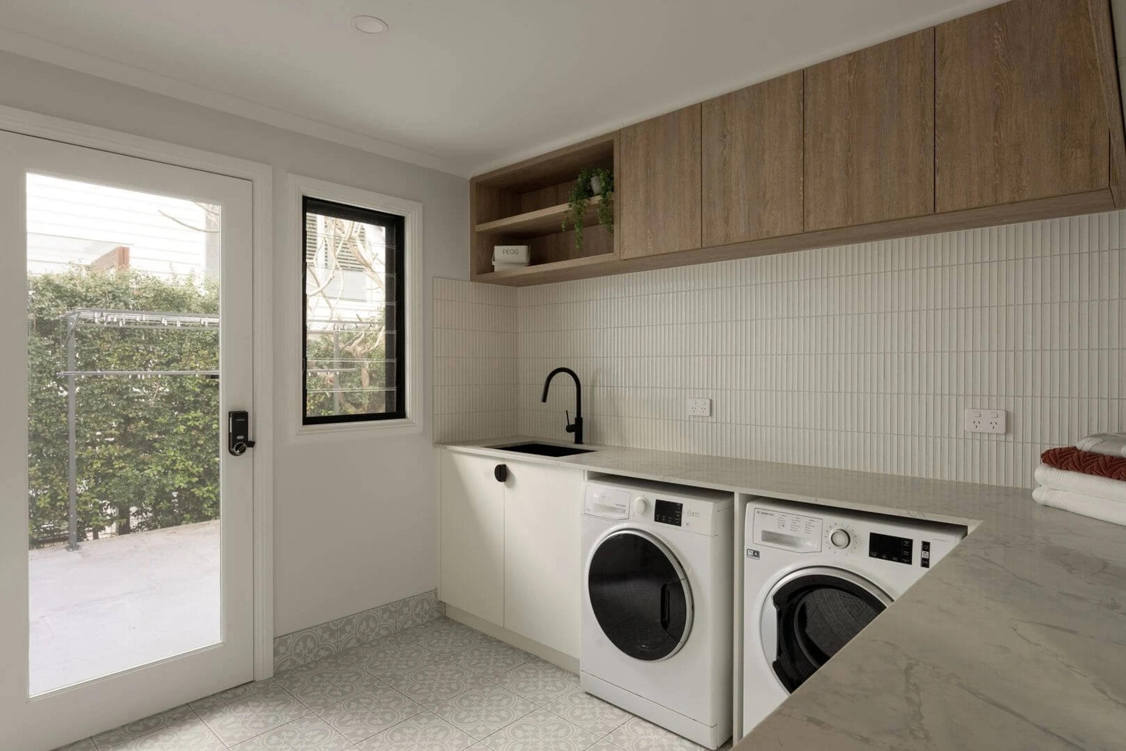 Laundry with side by side machines, marble bench and glass door