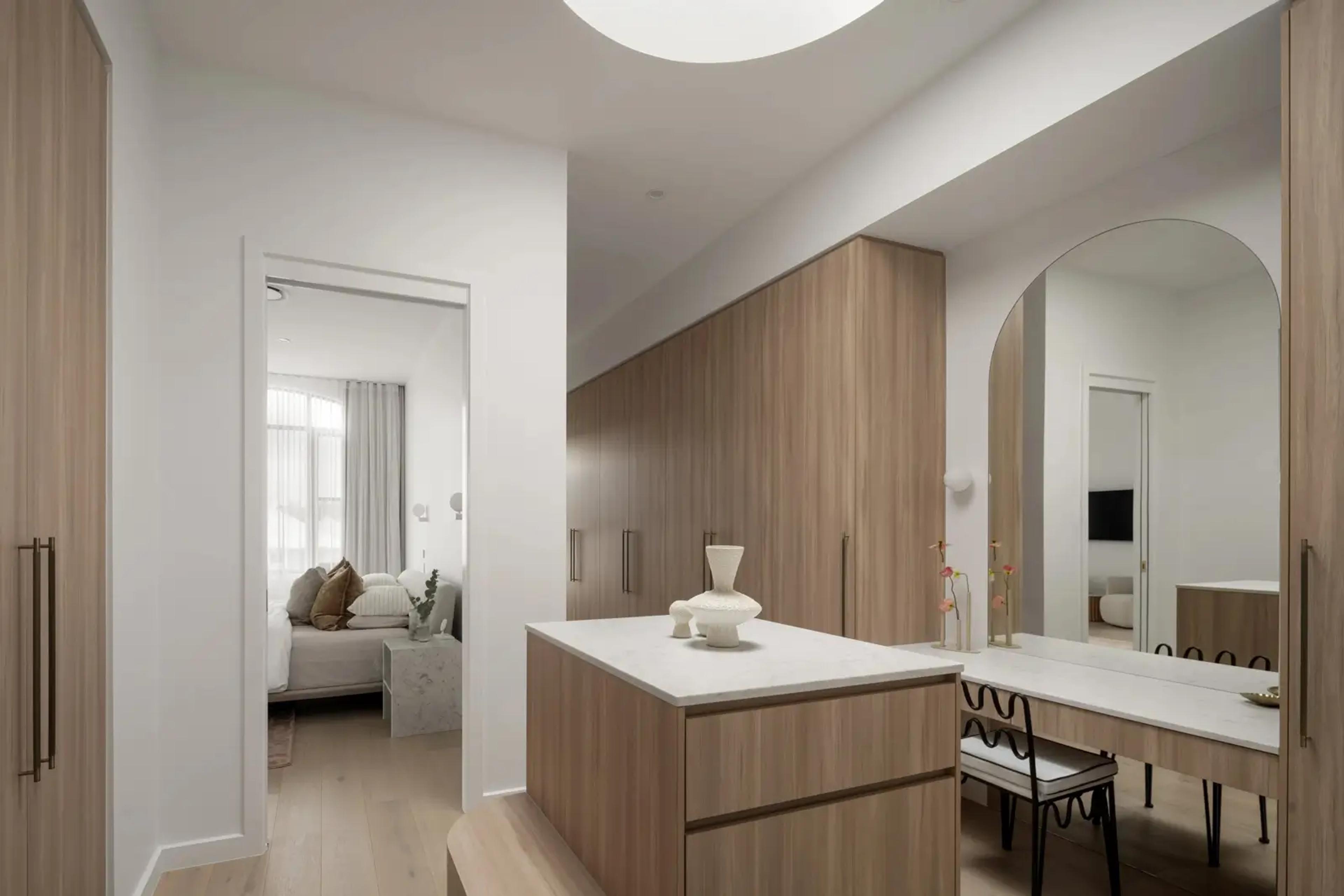 Dressing room with timber joinery, island bench and arched mirror