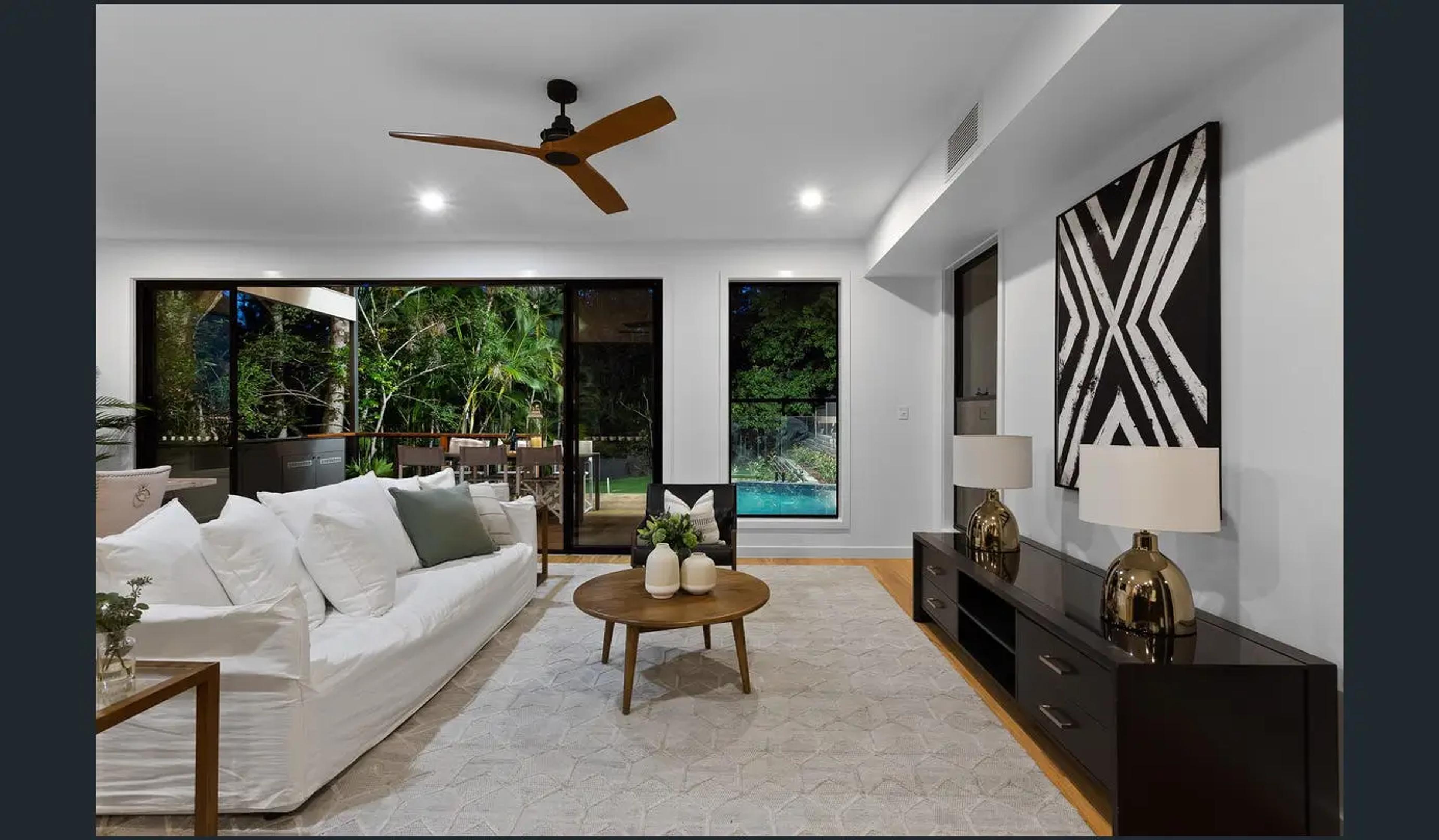 Living room with white sofa opening to pool and greenery