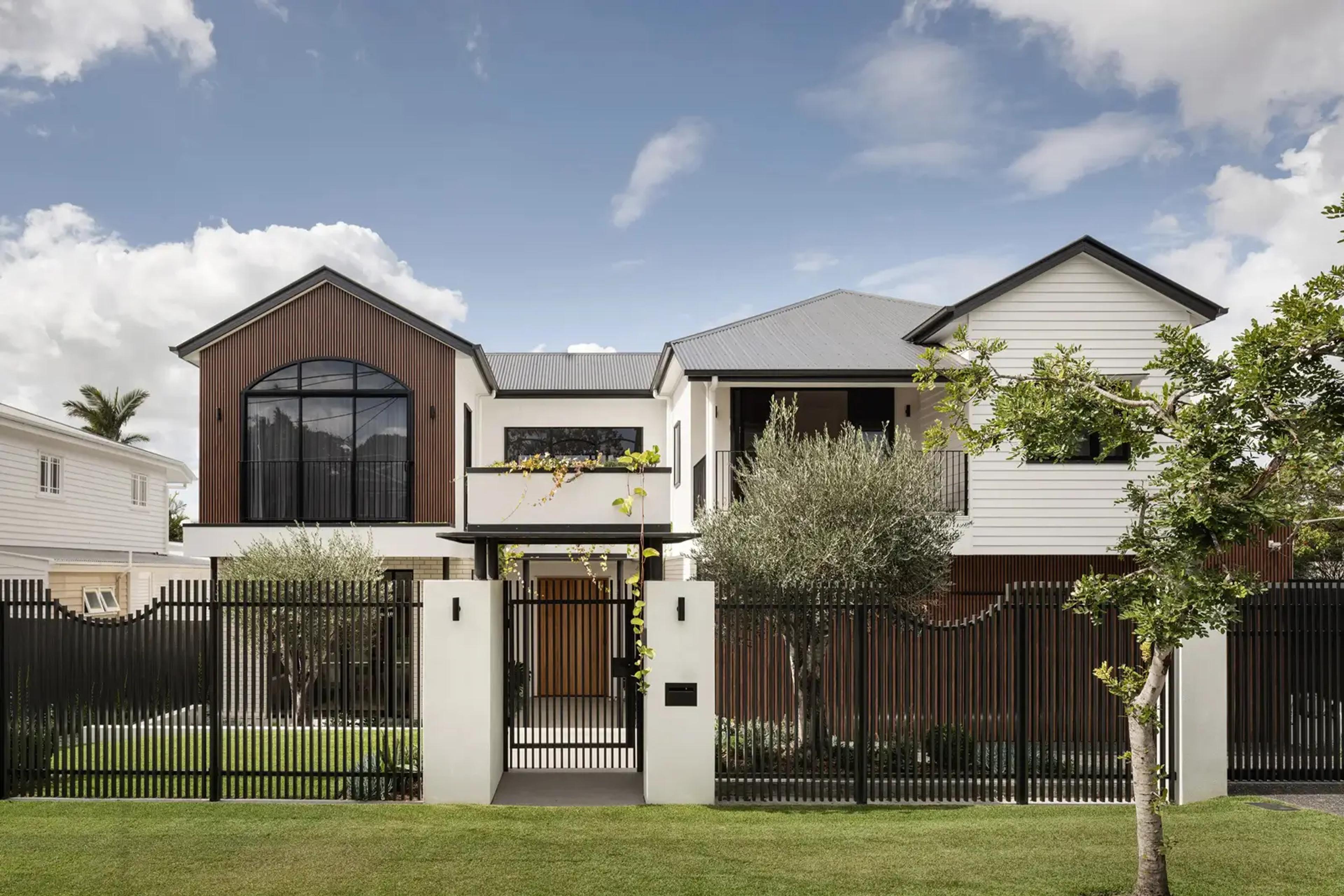 Street facing facade of two storey home behind black picket fence