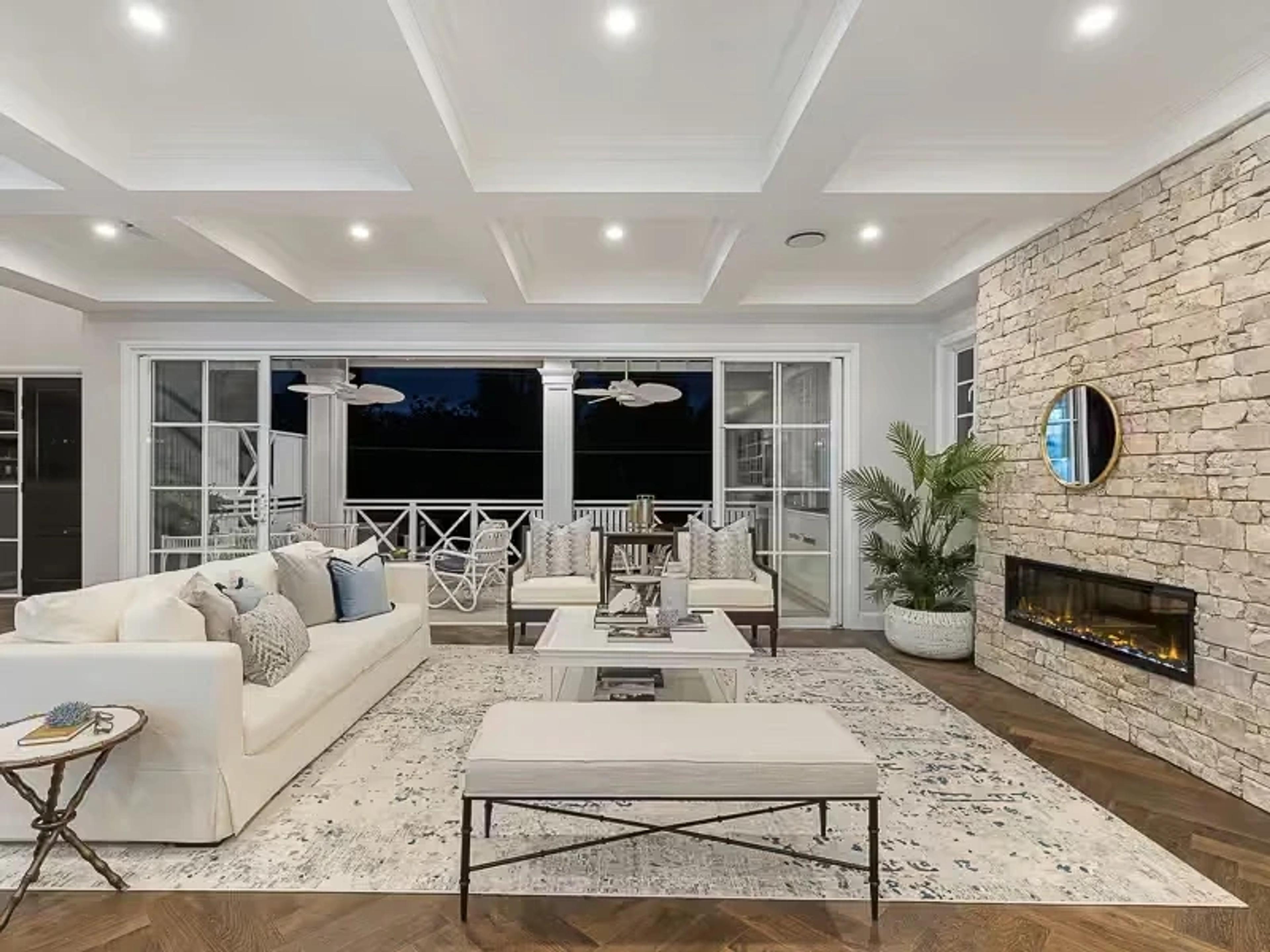 Living room with stone fireplace and balcony at dusk