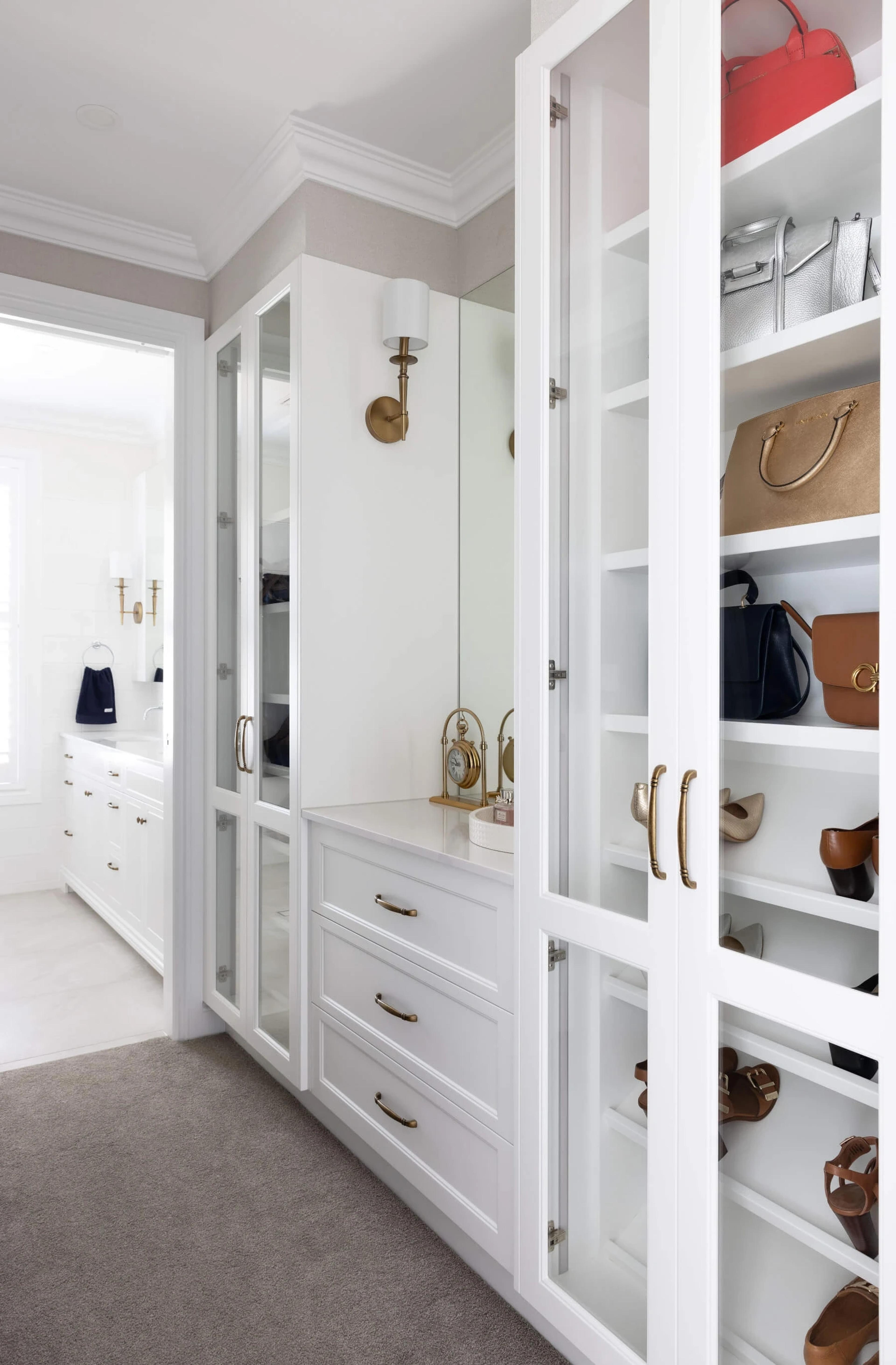Walk in wardrobe with glass fronted cabinets and shelving