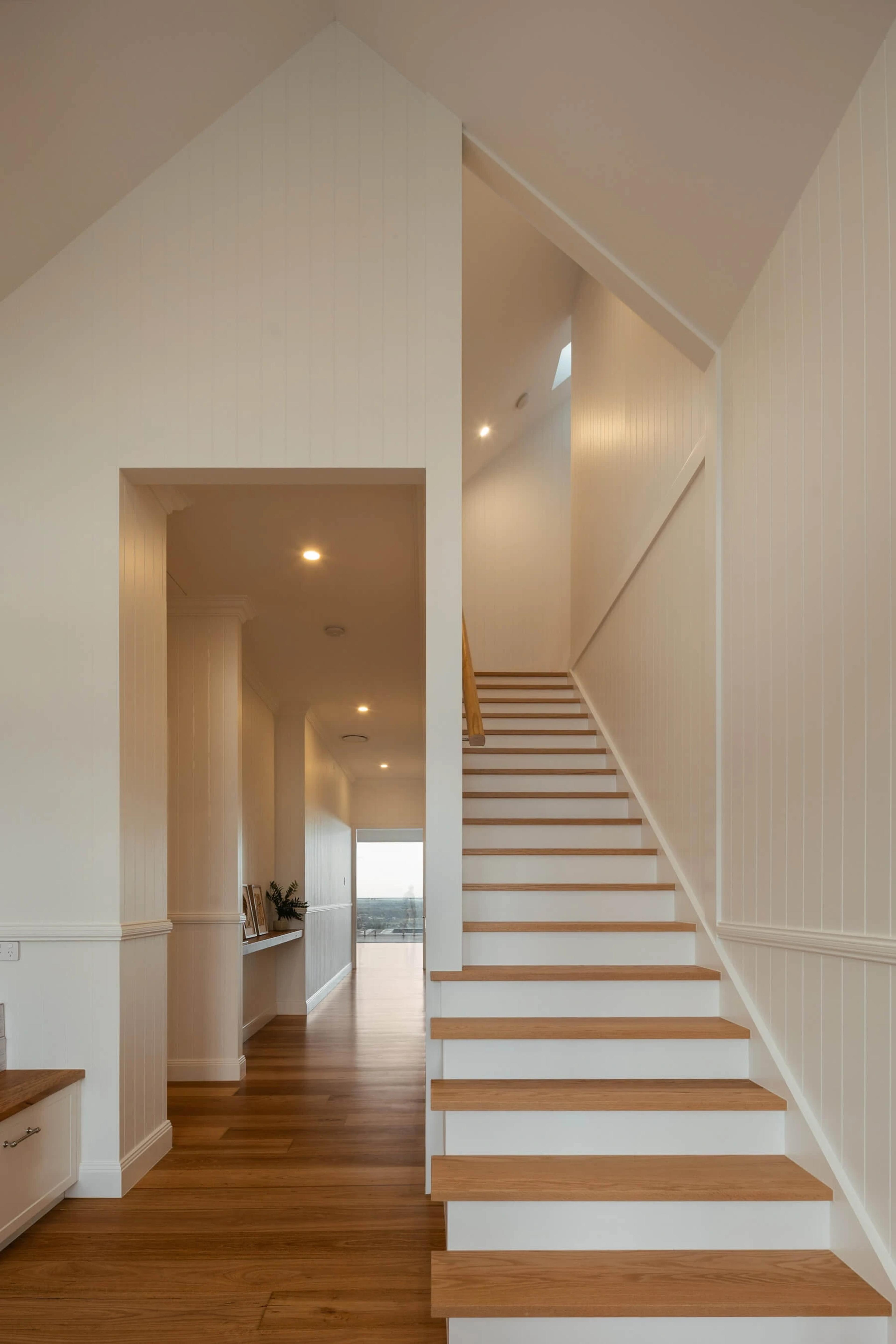 Bright entry hallway with timber staircase and vaulted ceiling