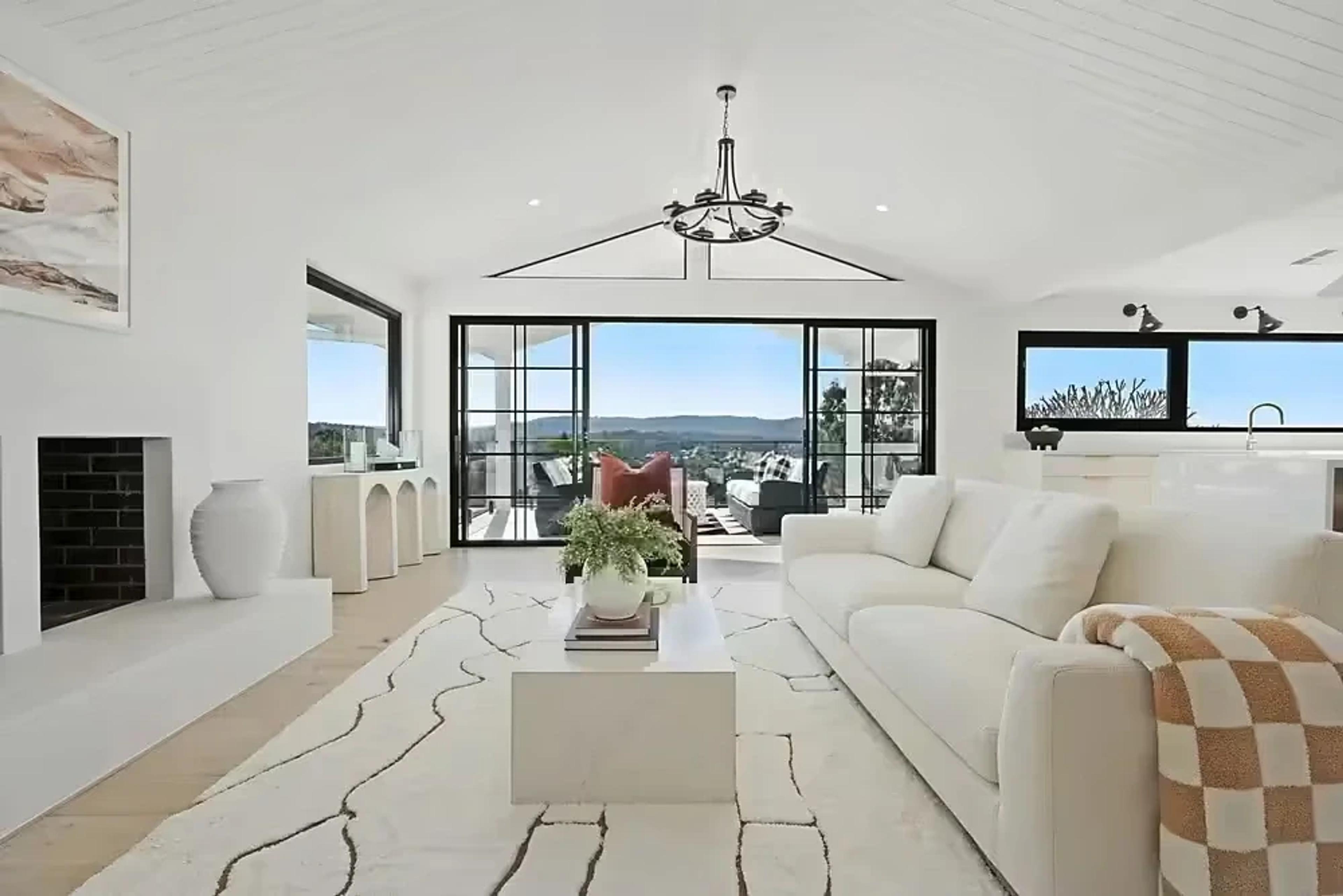 White living room with fireplace and valley views through black glazing.