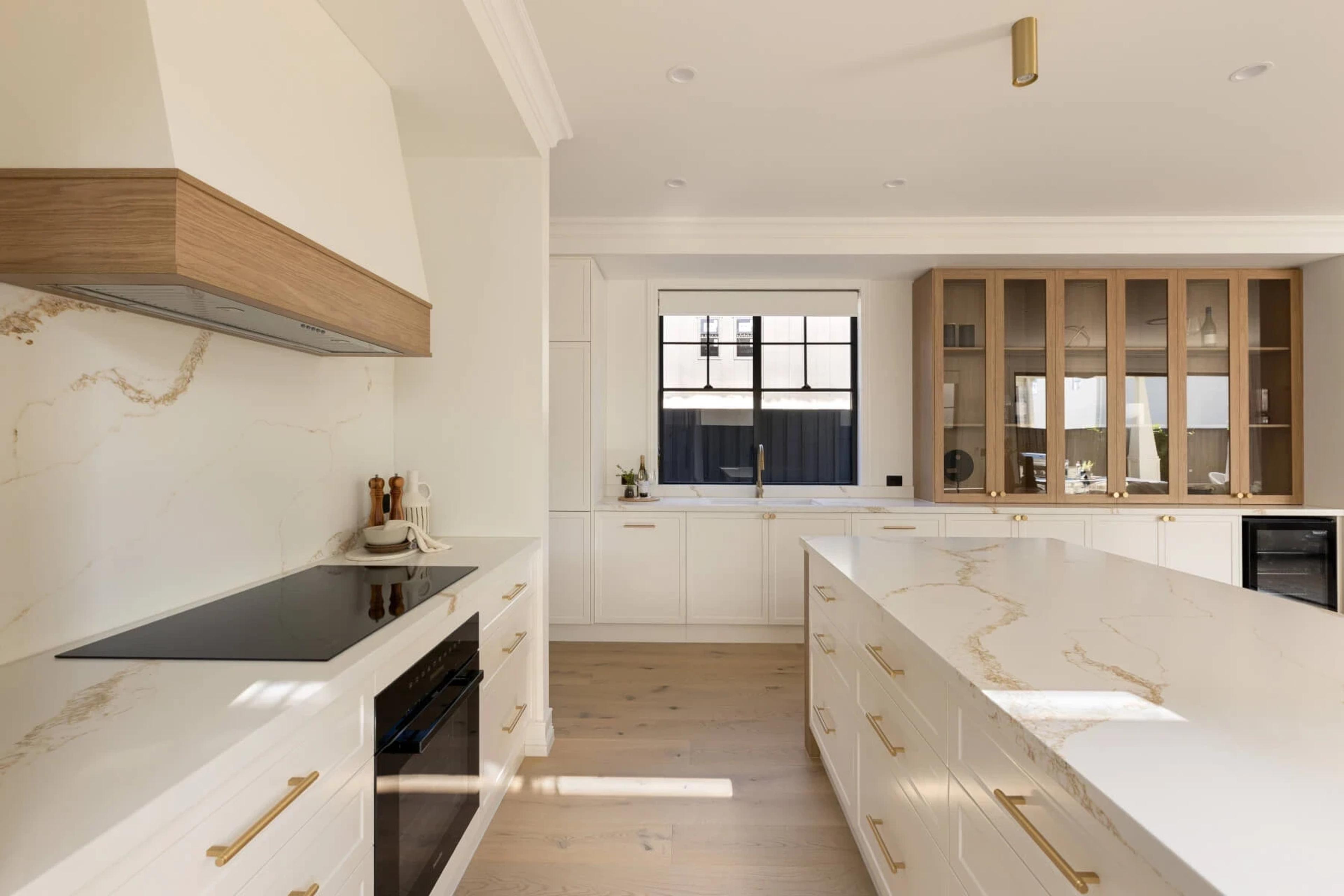 White kitchen with stone benchtops, timber rangehood and island bench