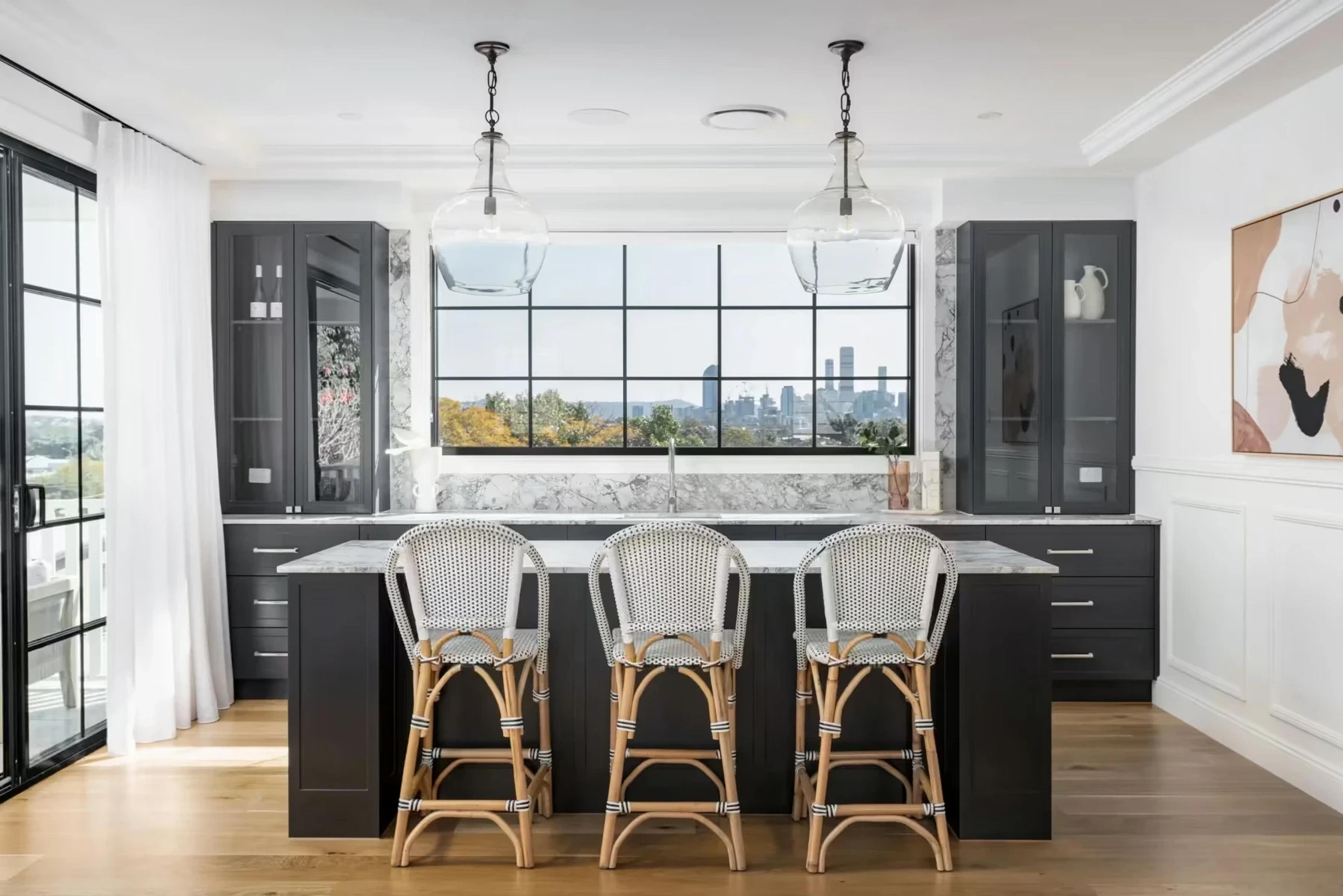 Monochrome kitchen with island, rattan stools and city skyline view
