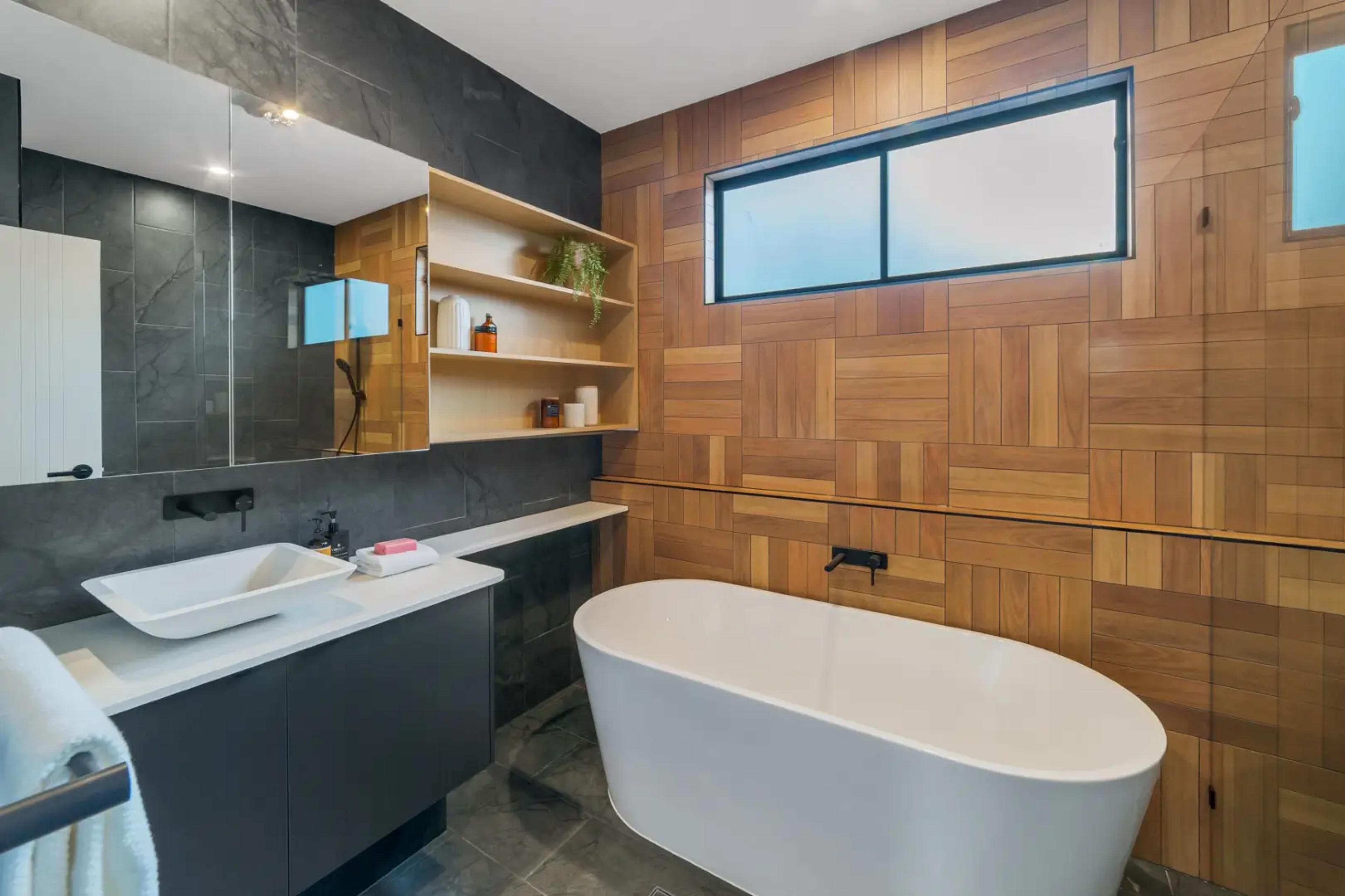 Bathroom with freestanding tub against timber tiled feature wall