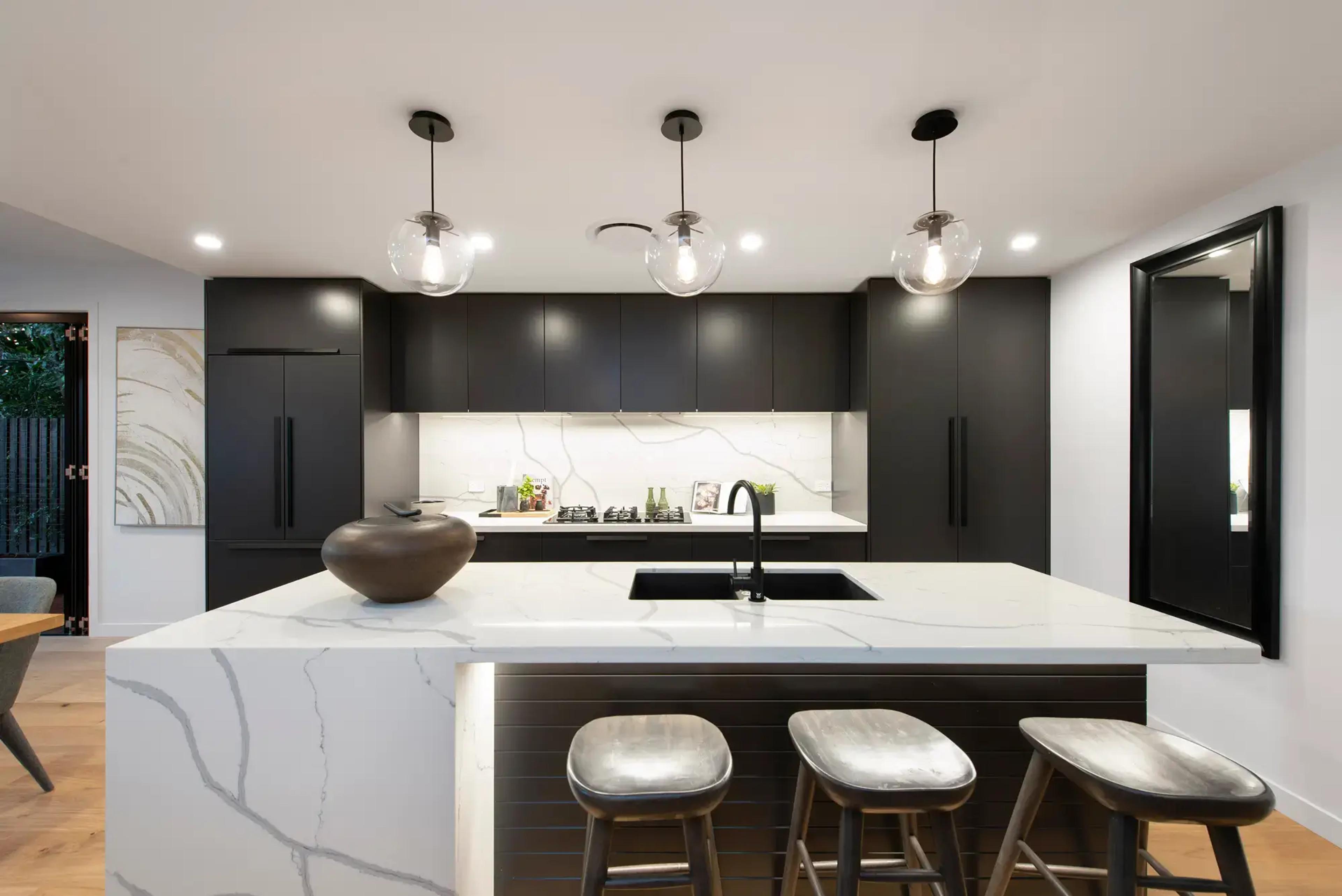 Black kitchen with marble island and pendant lights