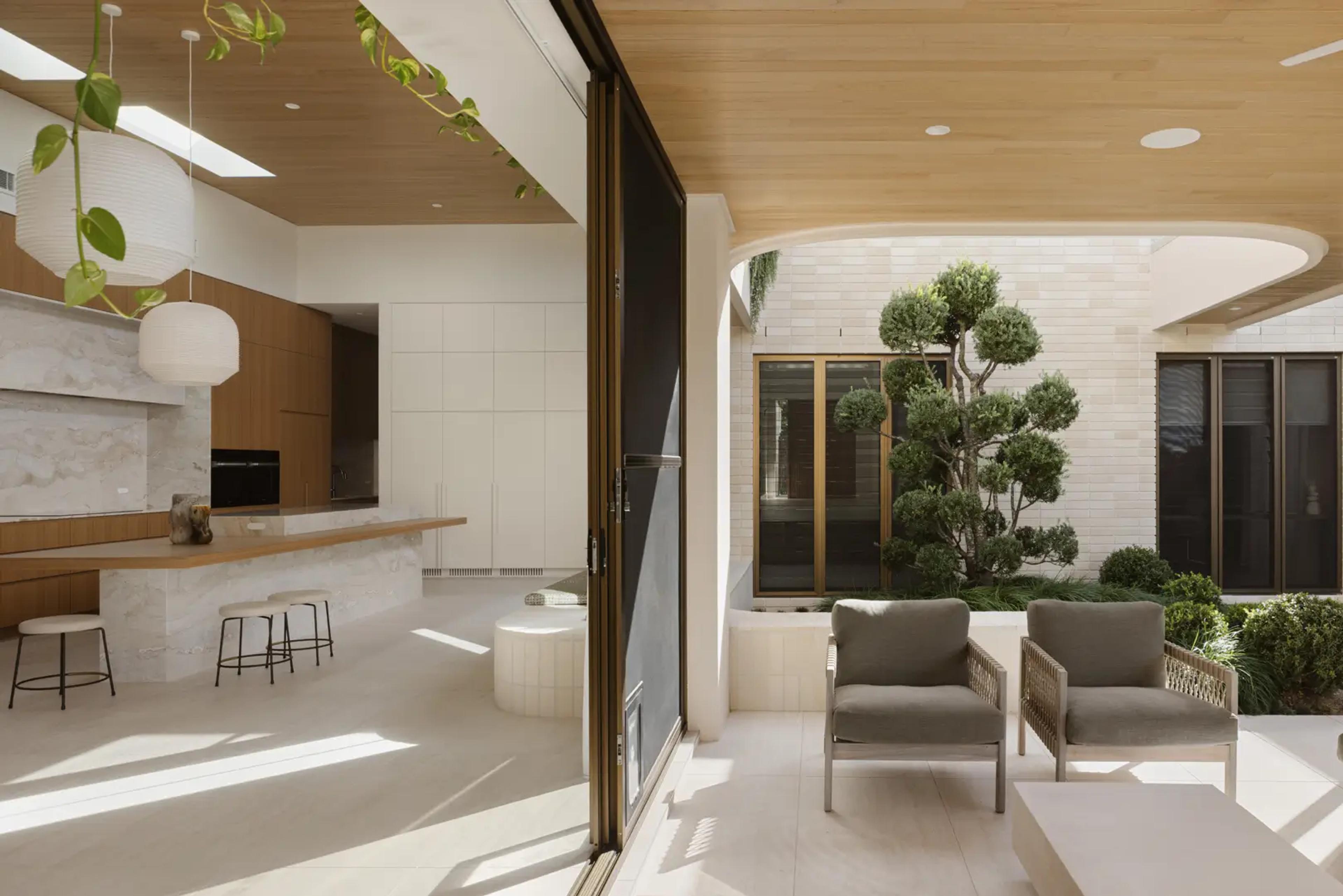 Covered terrace with armchairs beside courtyard and kitchen