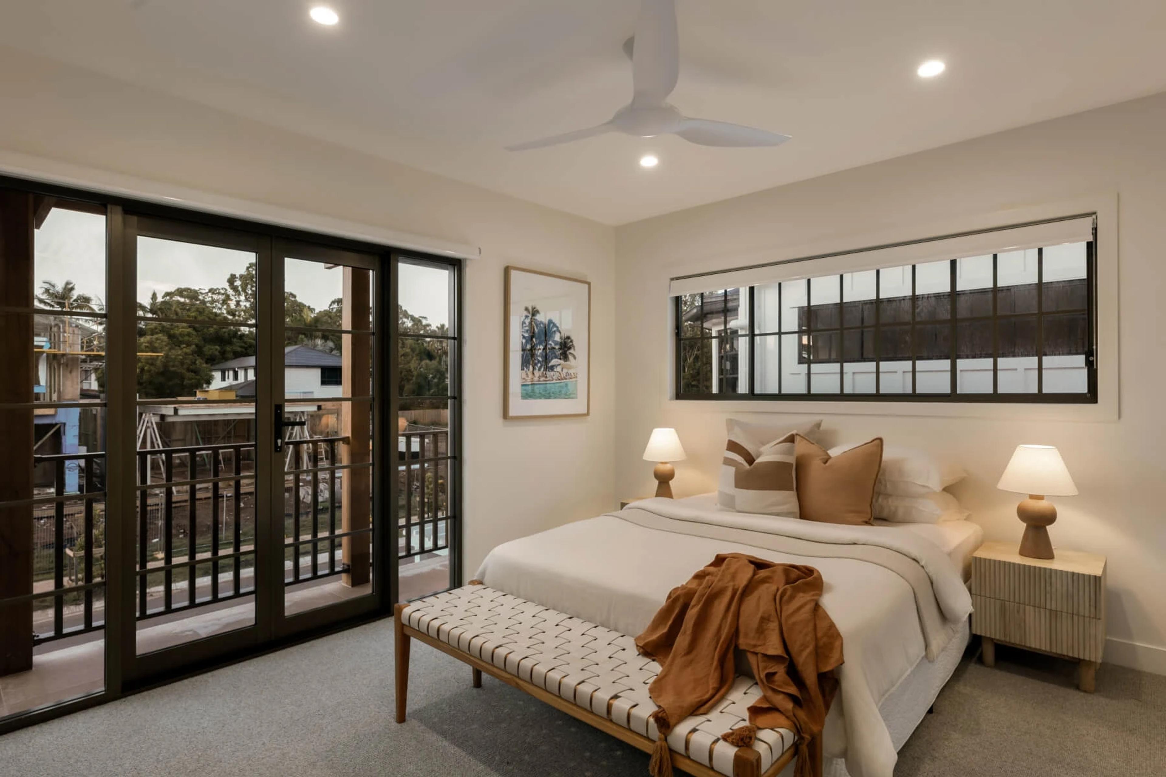 Bedroom with balcony doors, black framed windows and suburban view