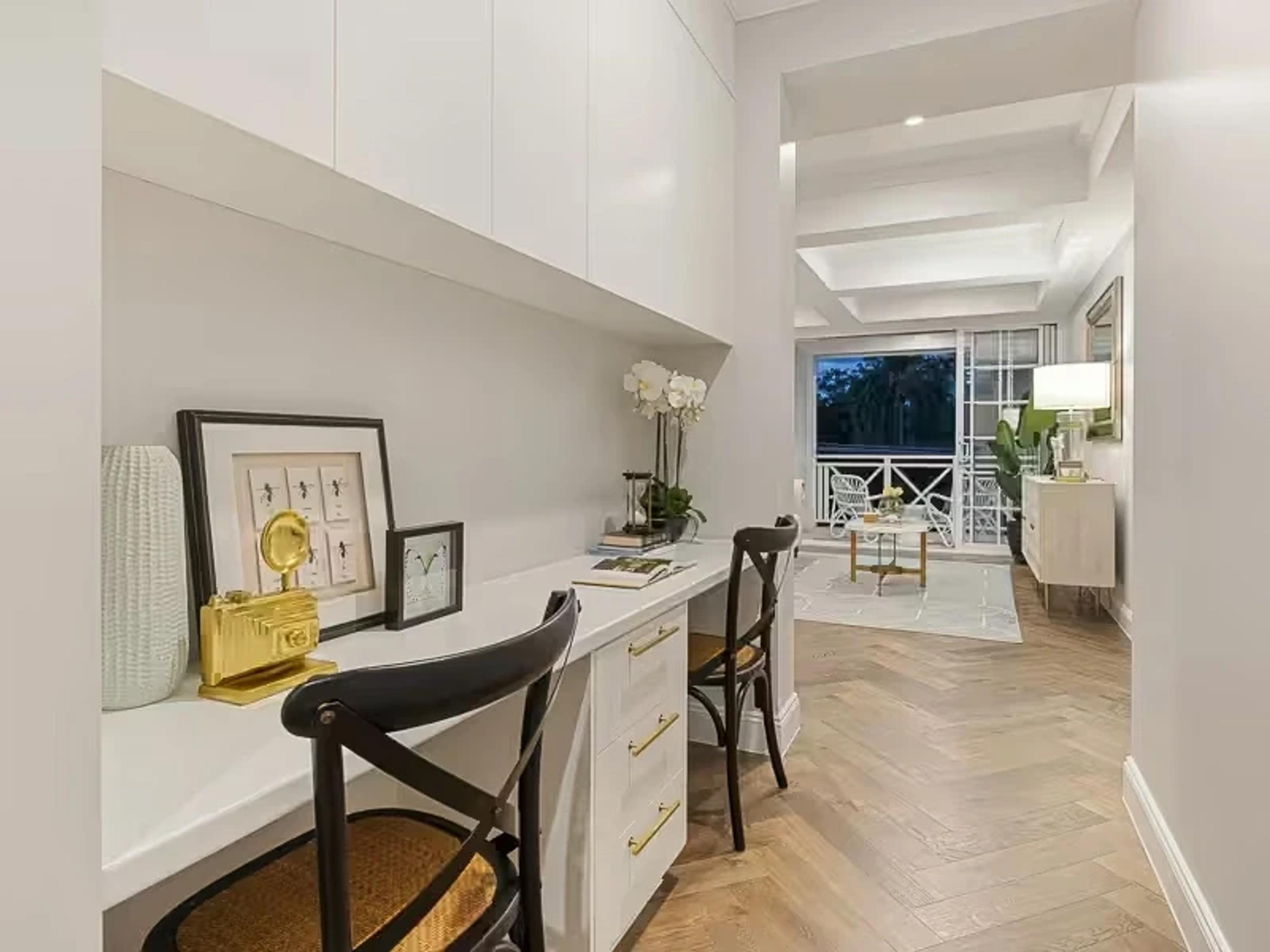 Built in study nook with white desk beside a sitting room