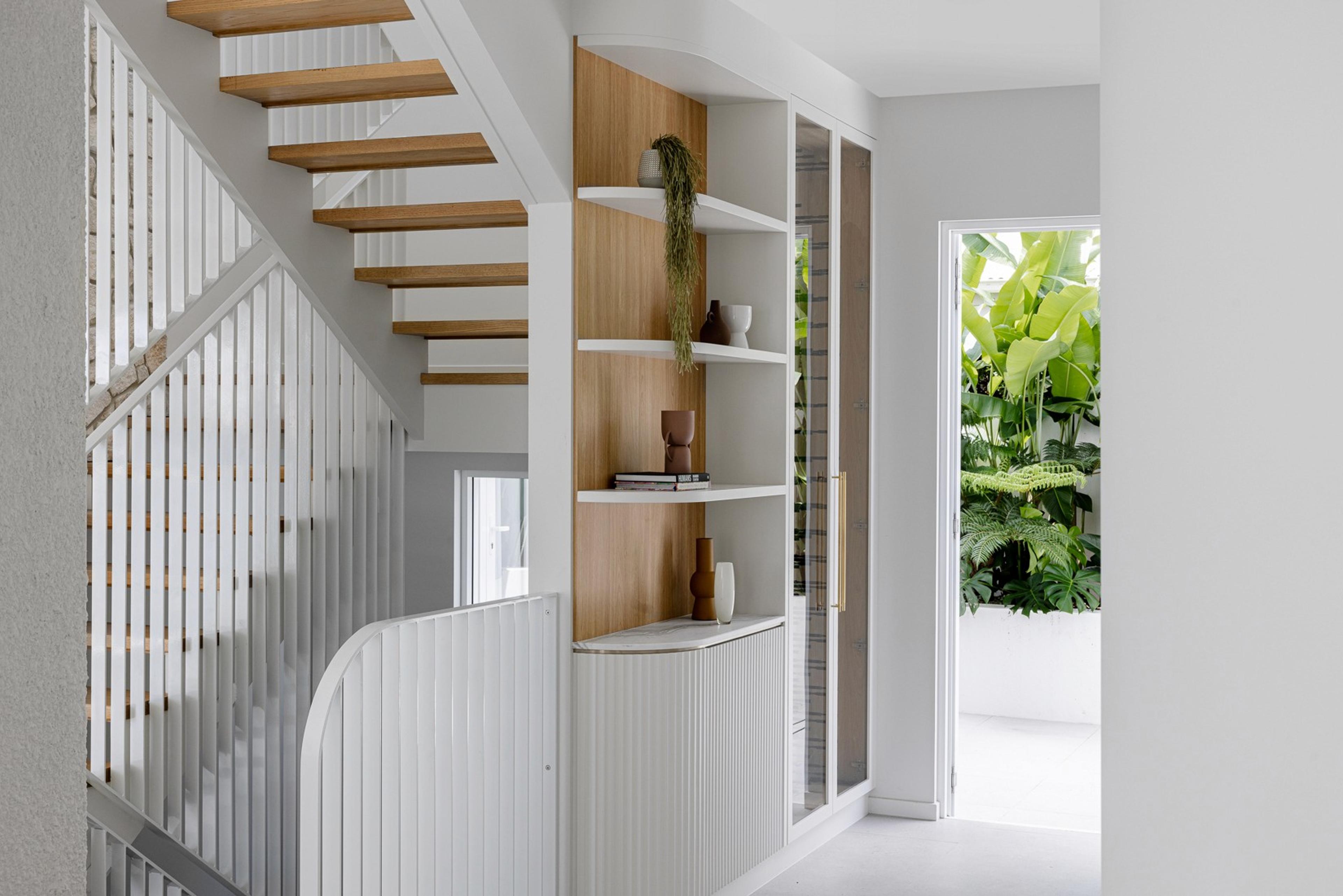 Timber and white staircase beside built in shelving near entry