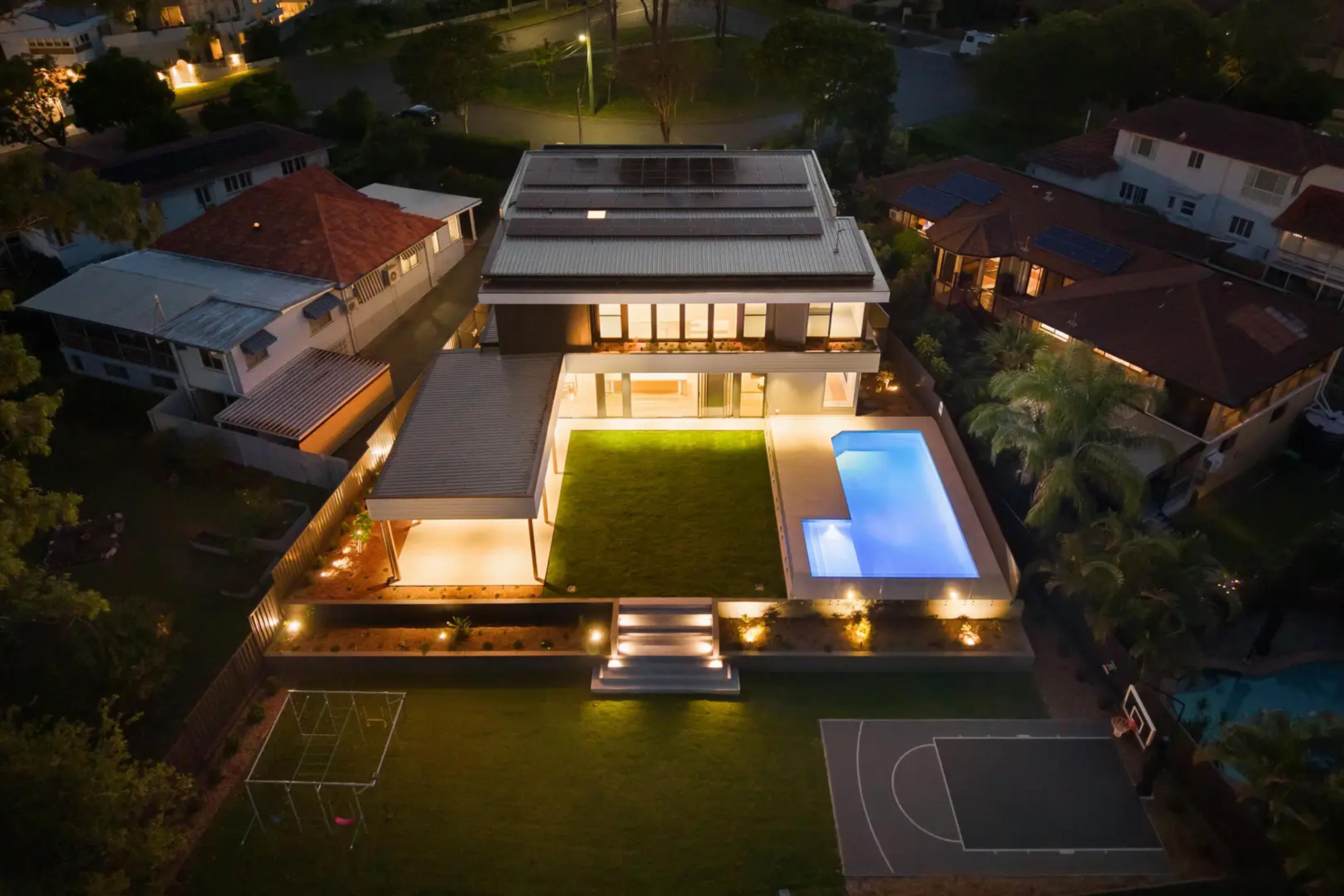 Aerial night view of home with pool and courts