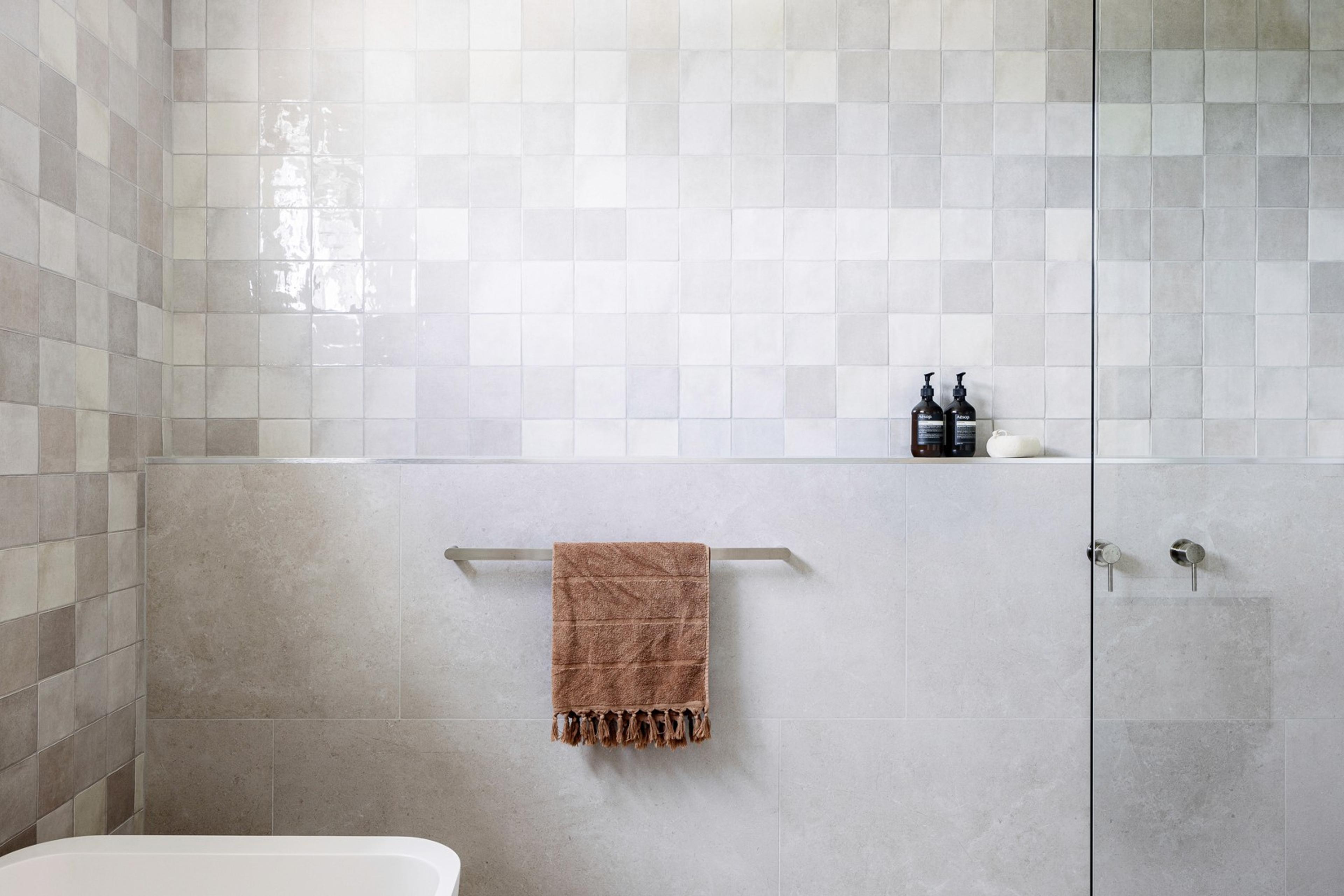 Tiled bathroom wall with shower rail and hanging towel