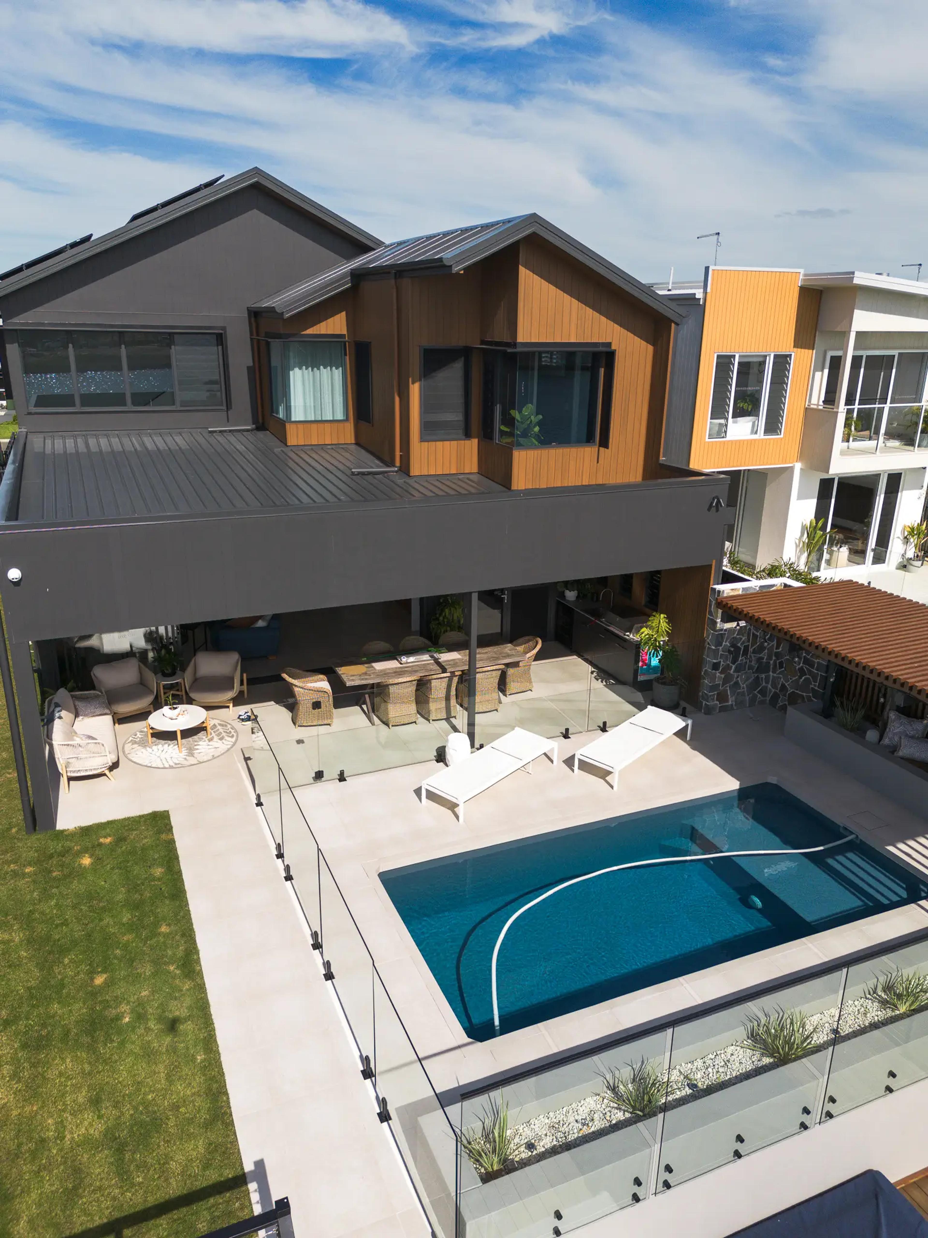 Aerial view of home rear with pool and water