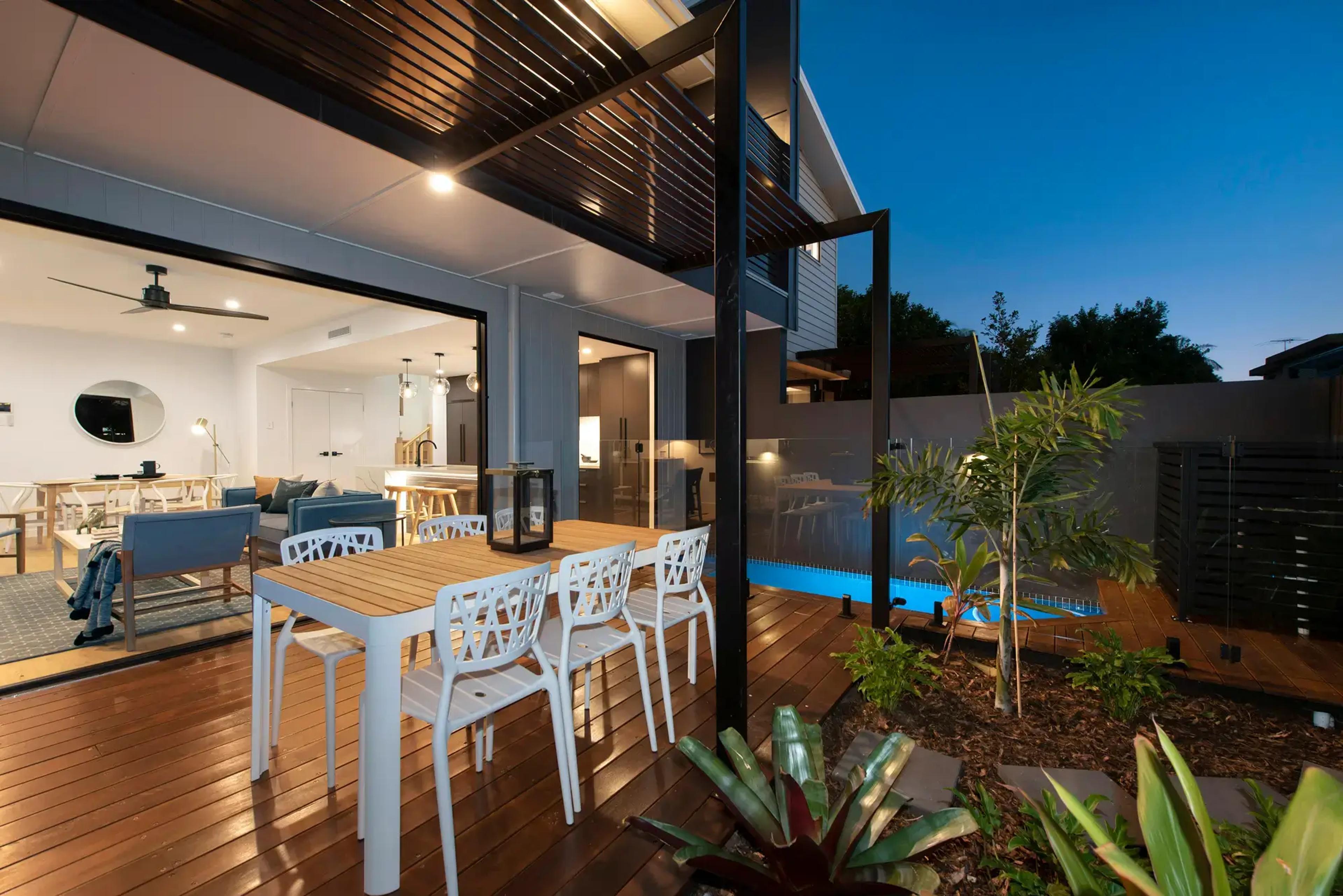 Rear deck with dining setting and pool at dusk