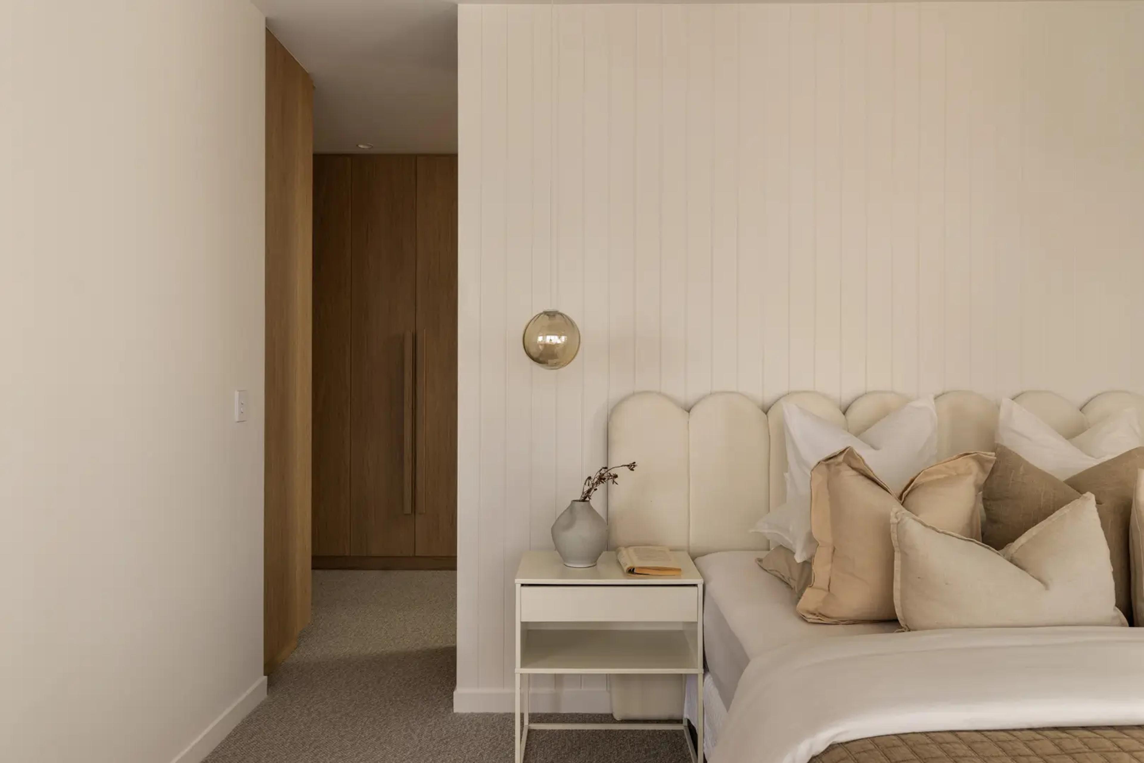 Main bedroom with upholstered bedhead and timber wardrobe