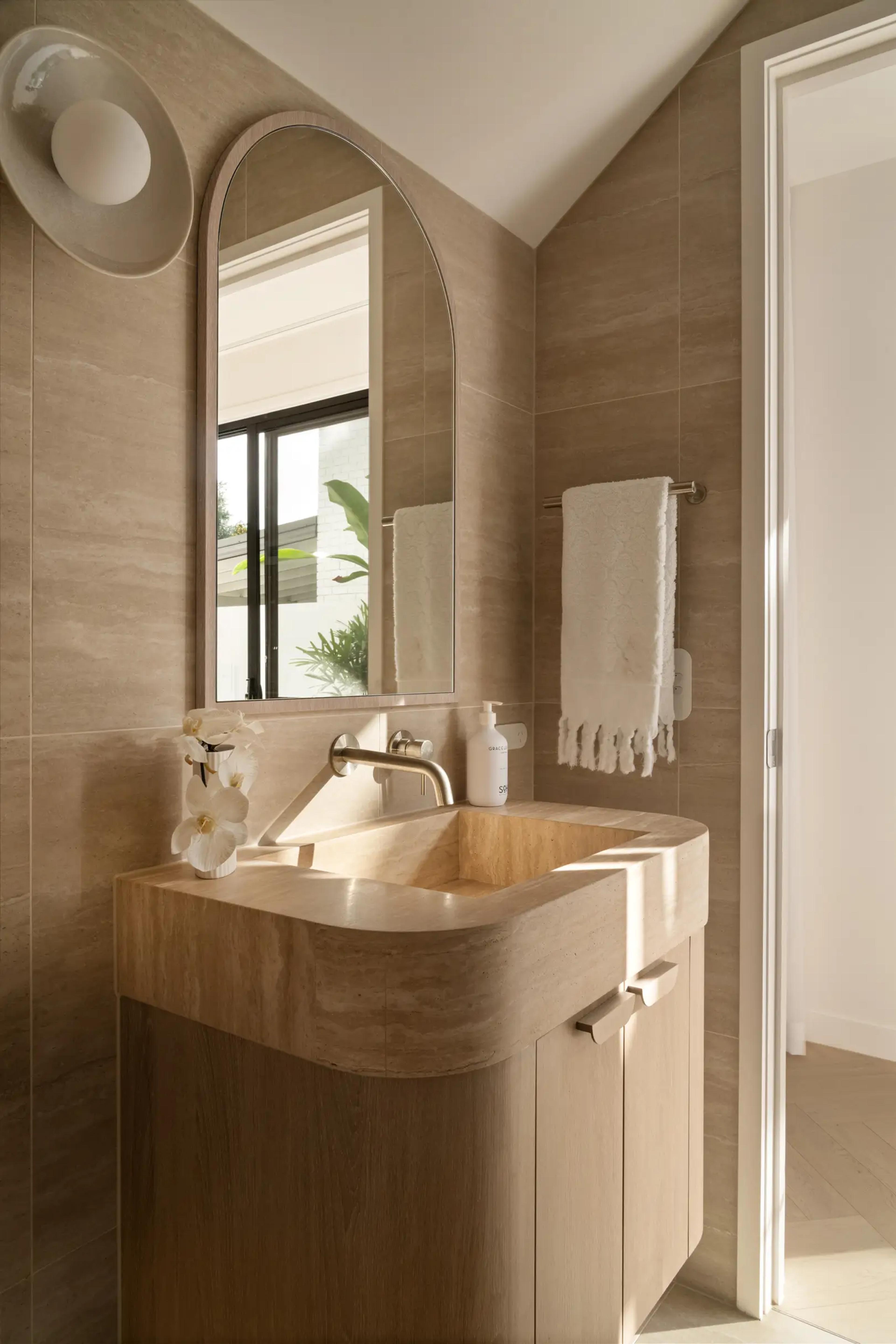 Powder room with stone basin and arched mirror