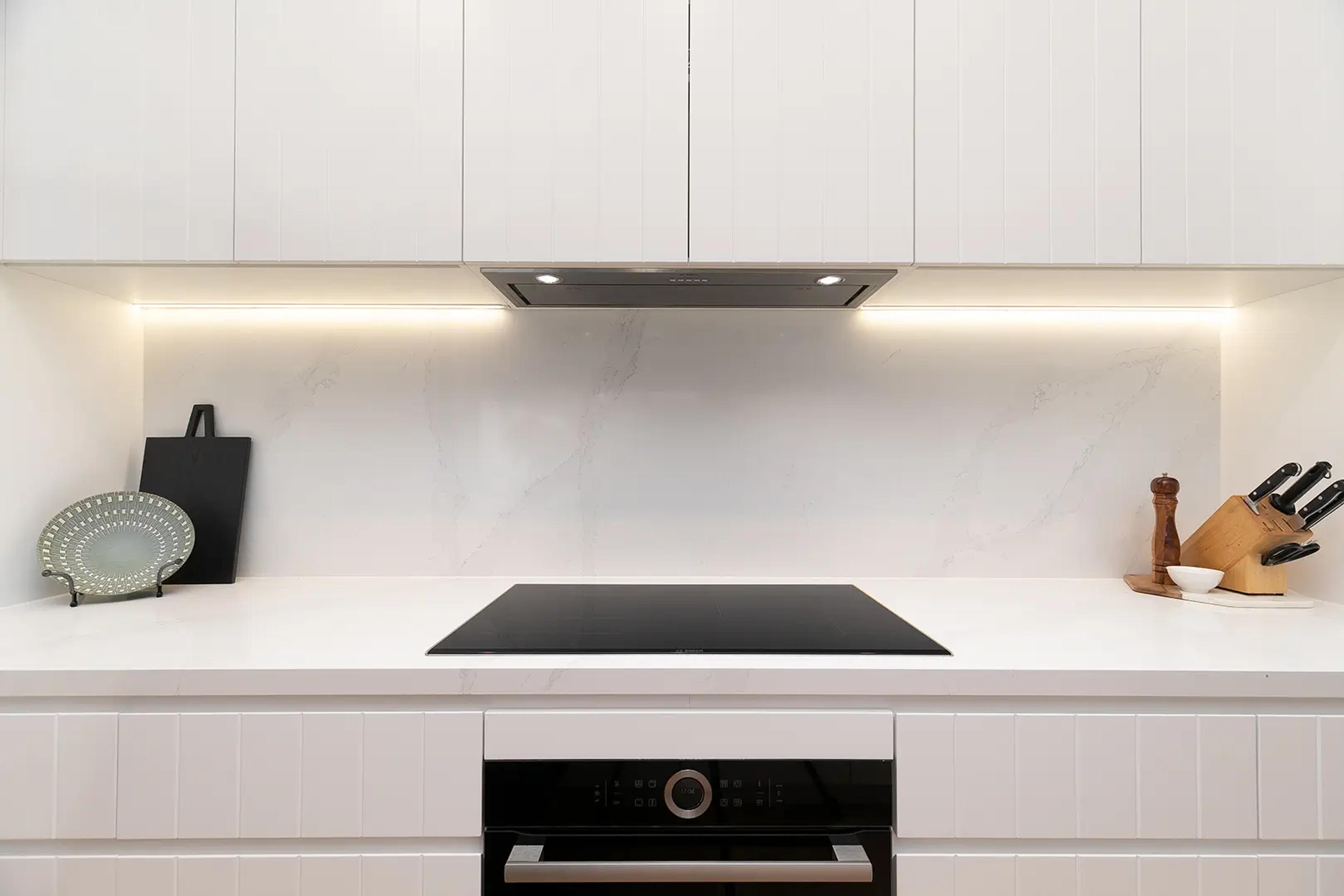 White kitchen splashback with induction cooktop and rangehood