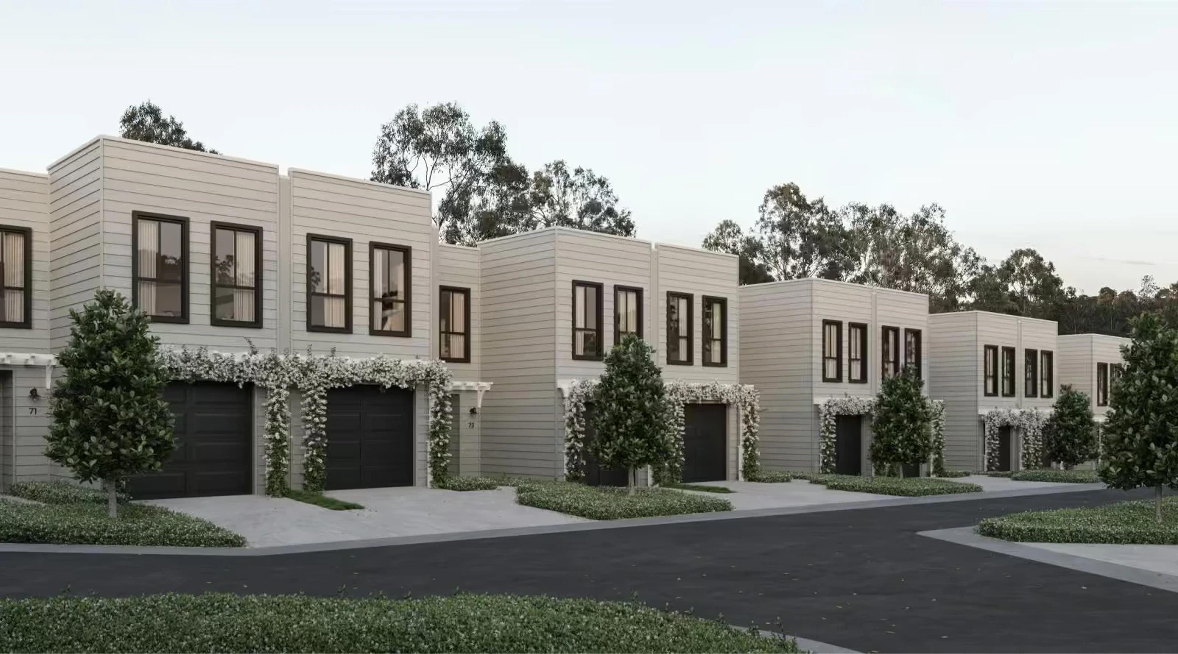Street view of white townhouses with dark garage doors