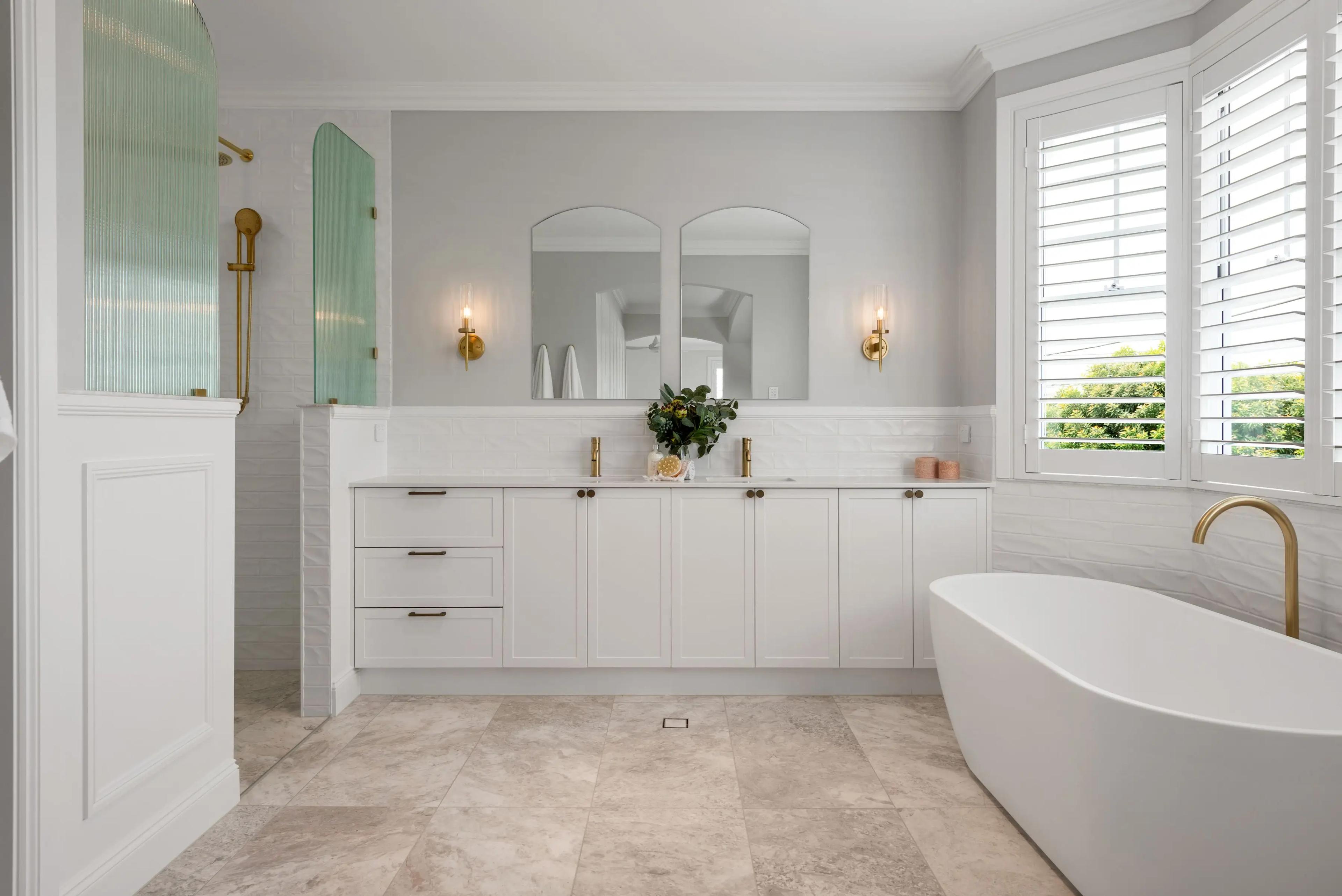 Bathroom with freestanding tub, twin mirrors and brass tapware