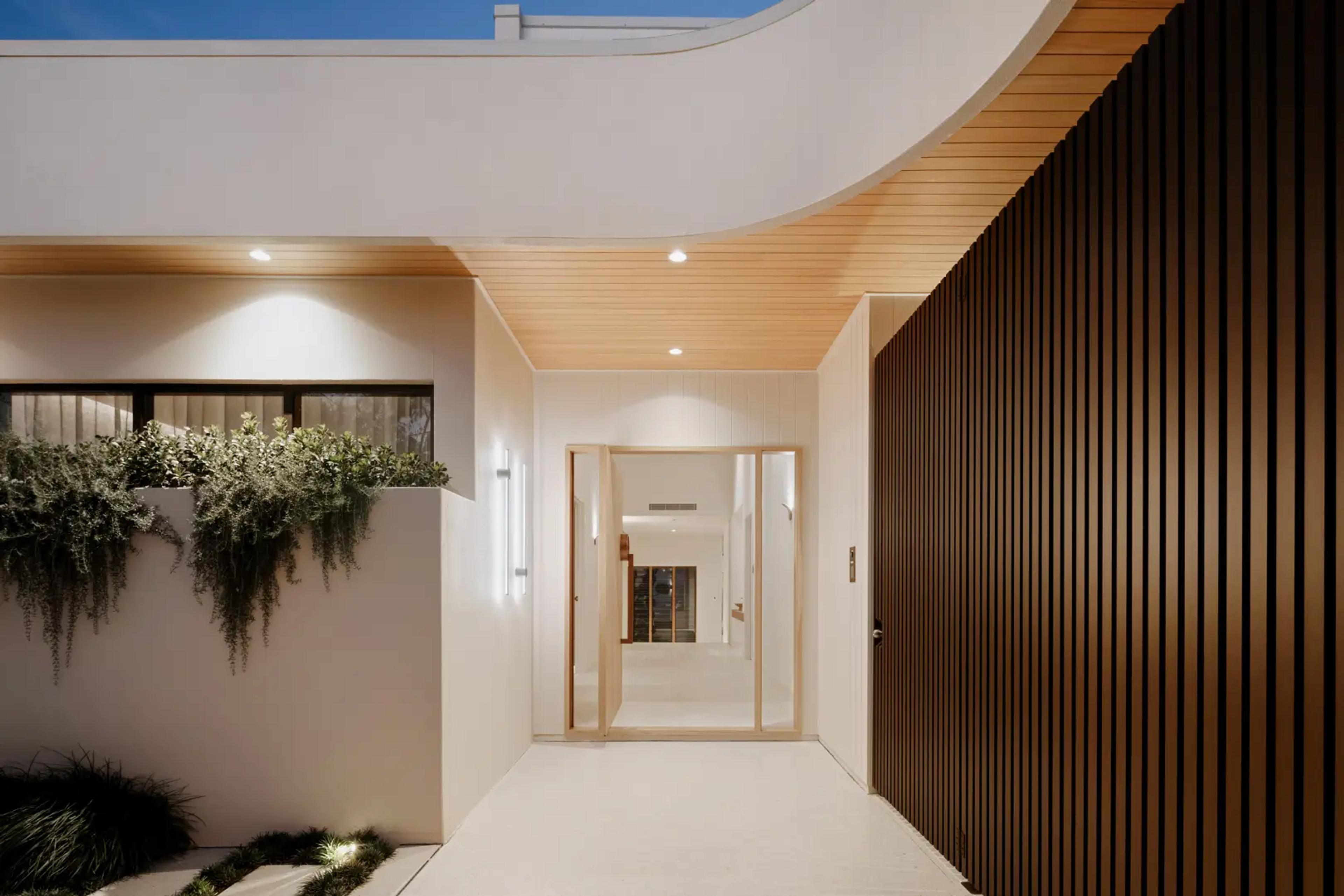 Covered entry walkway with timber ceiling and pivot door