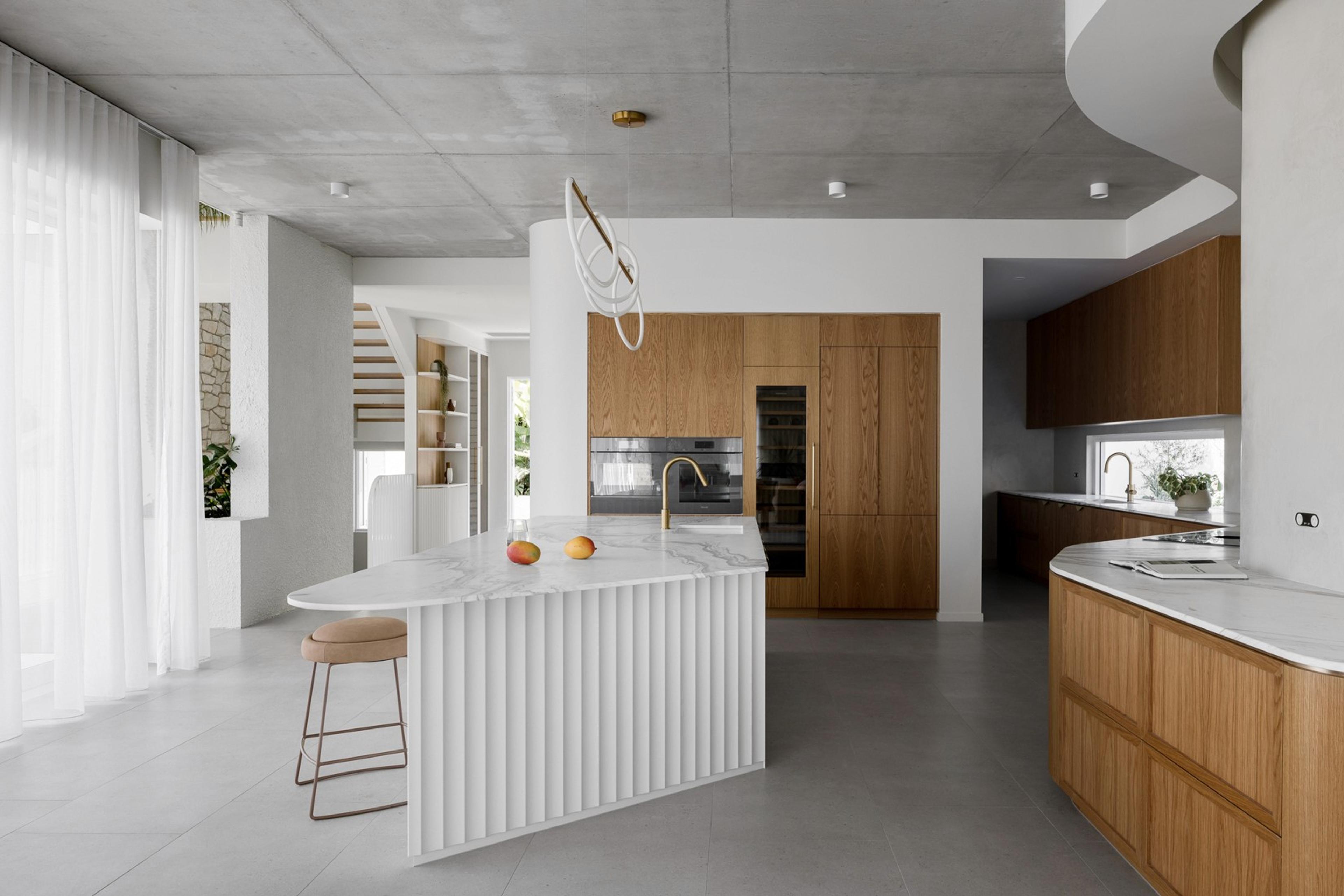Open kitchen with timber cabinetry and fluted stone island