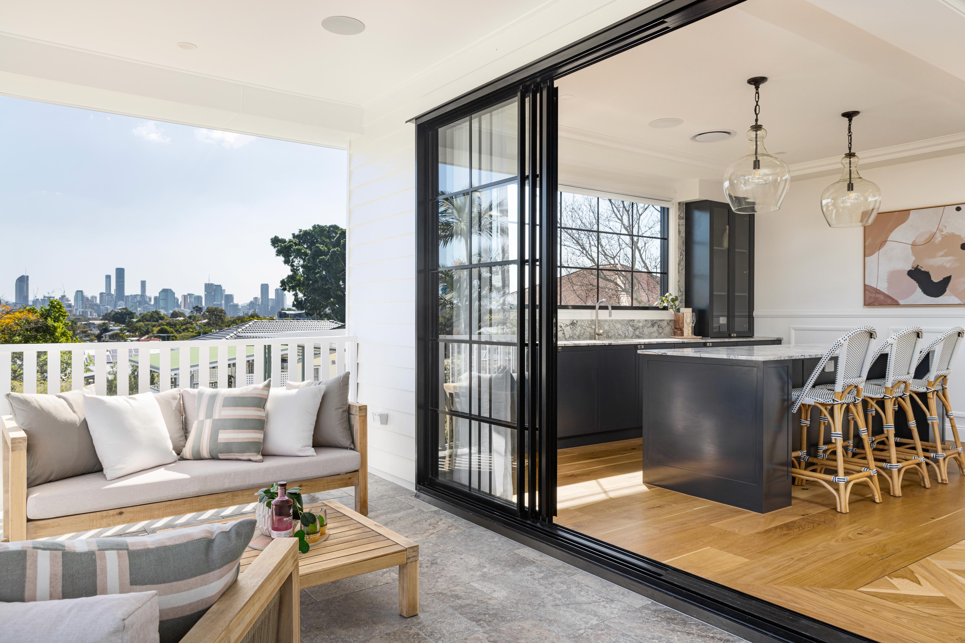 Covered balcony with lounge overlooking city skyline beside kitchen