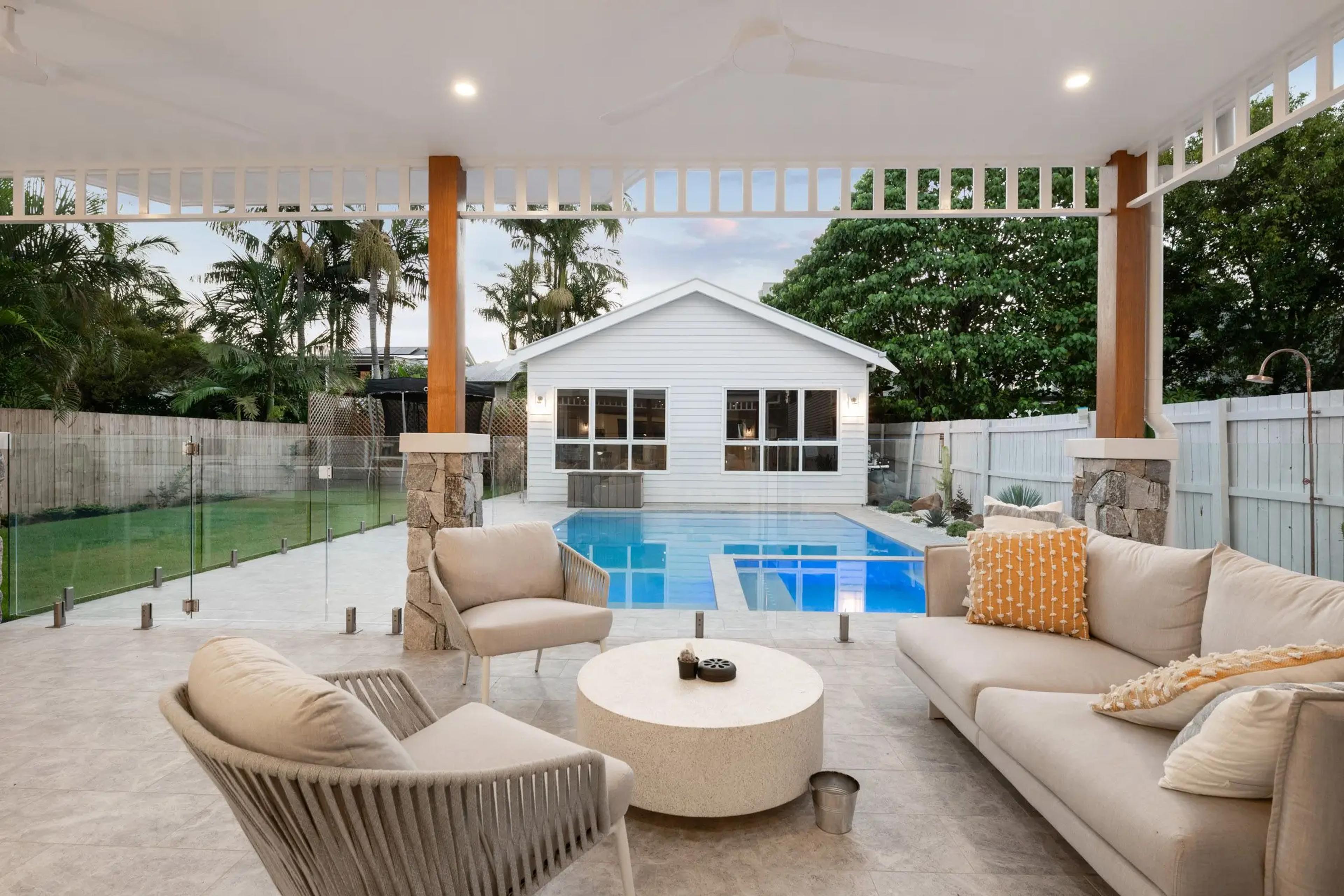 Covered outdoor lounge overlooking pool at dusk