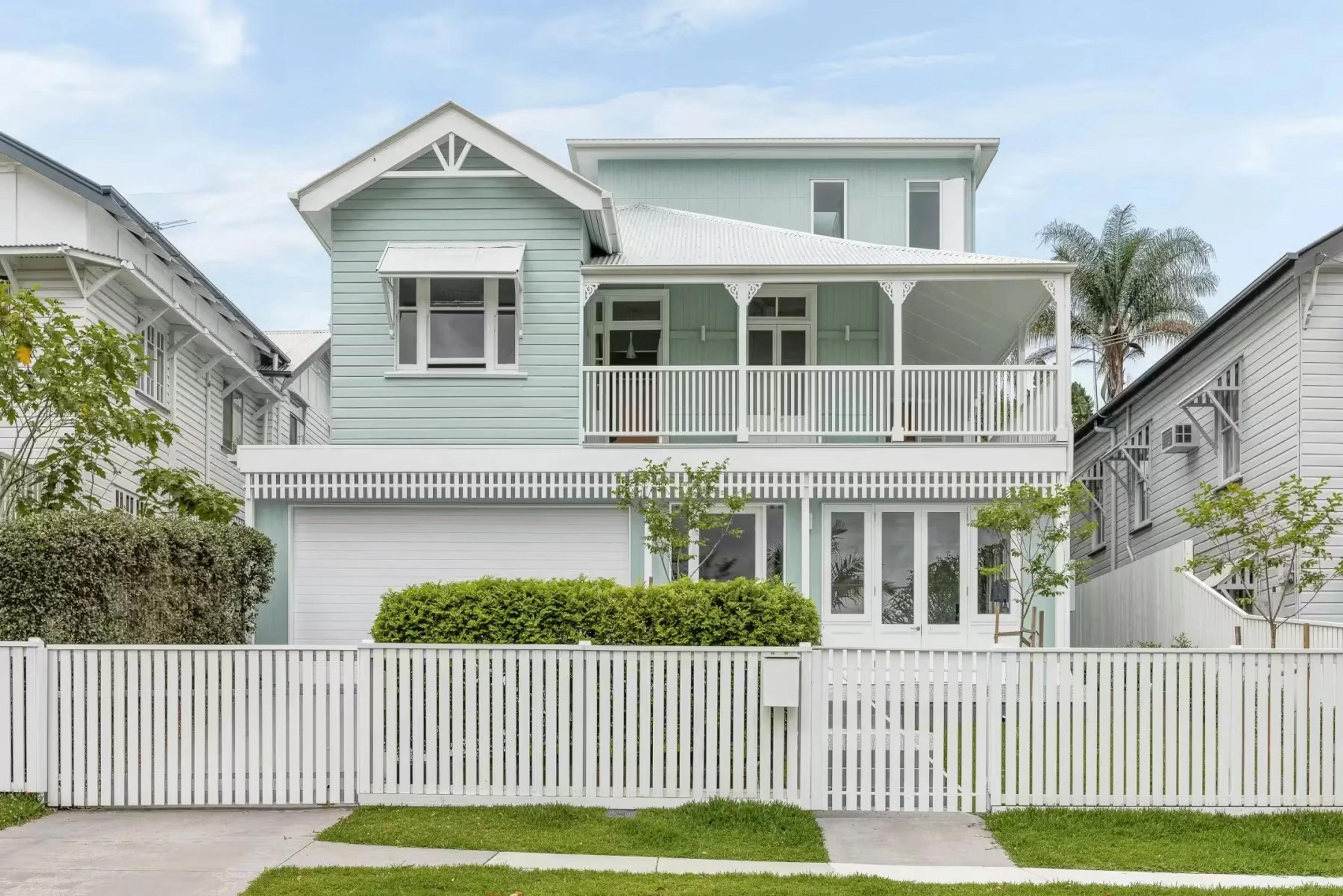 Two storey weatherboard Queenslander home with front verandah and picket fence
