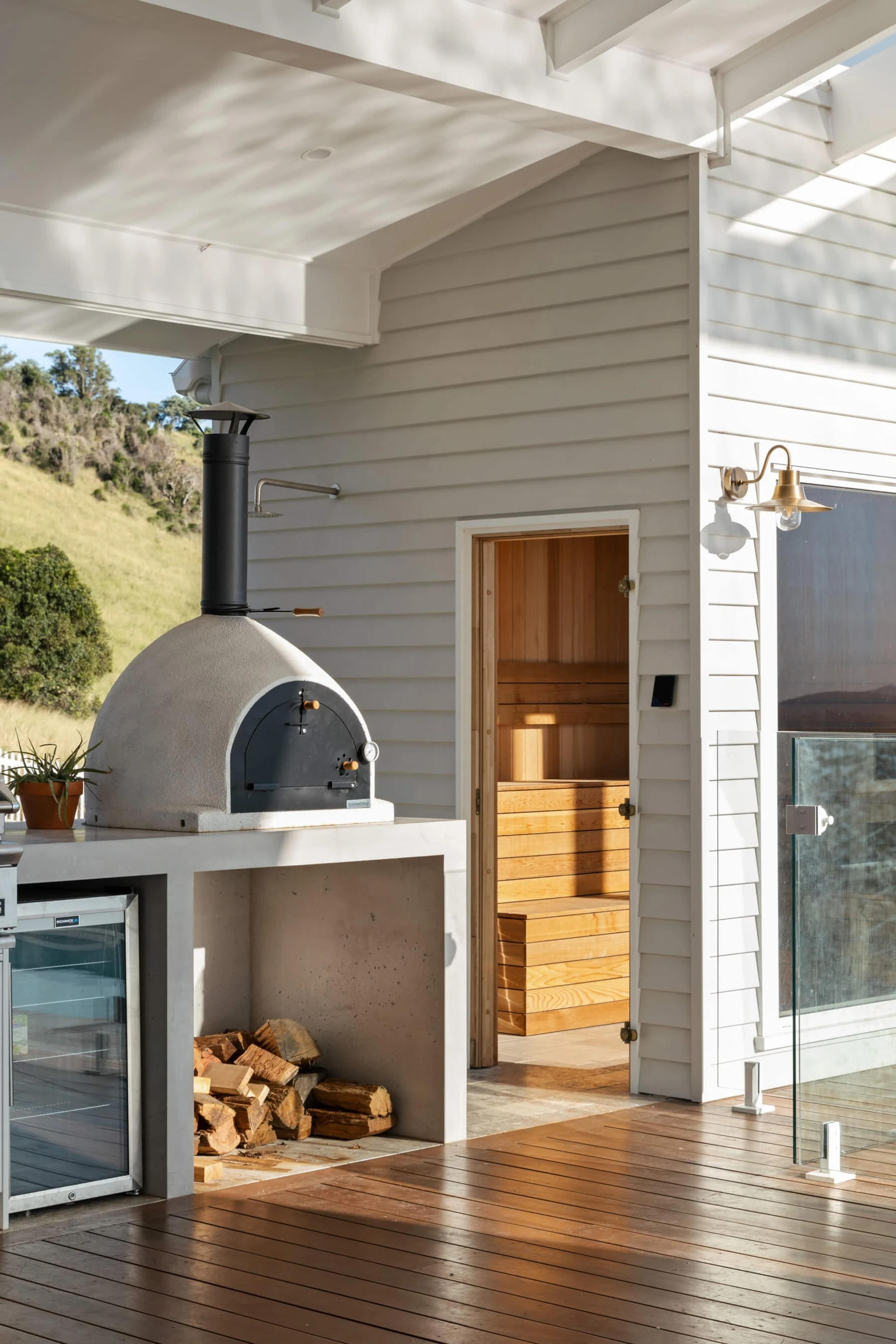 Outdoor pizza oven and sauna entry on covered timber deck