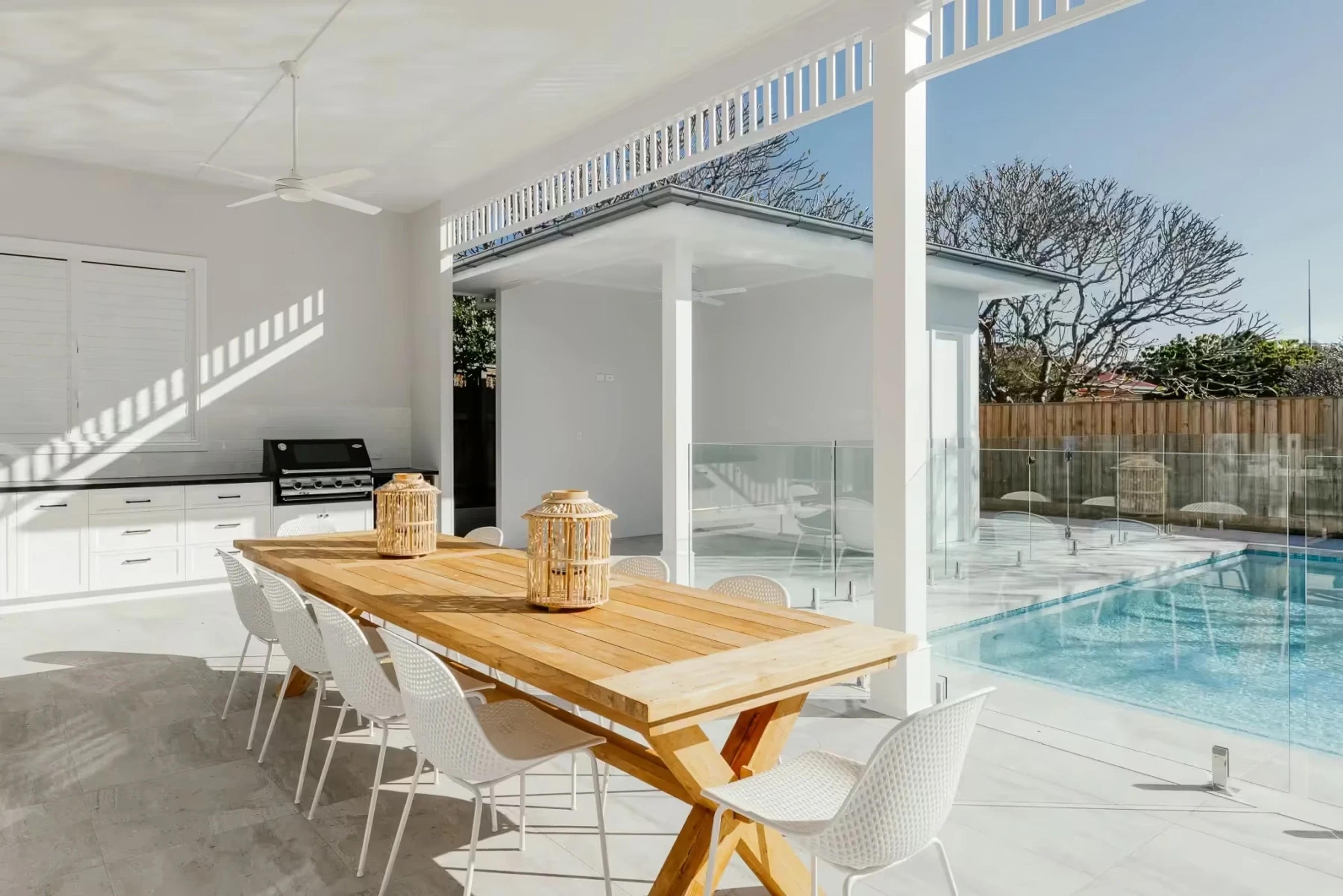 Covered alfresco dining area beside glass fenced pool