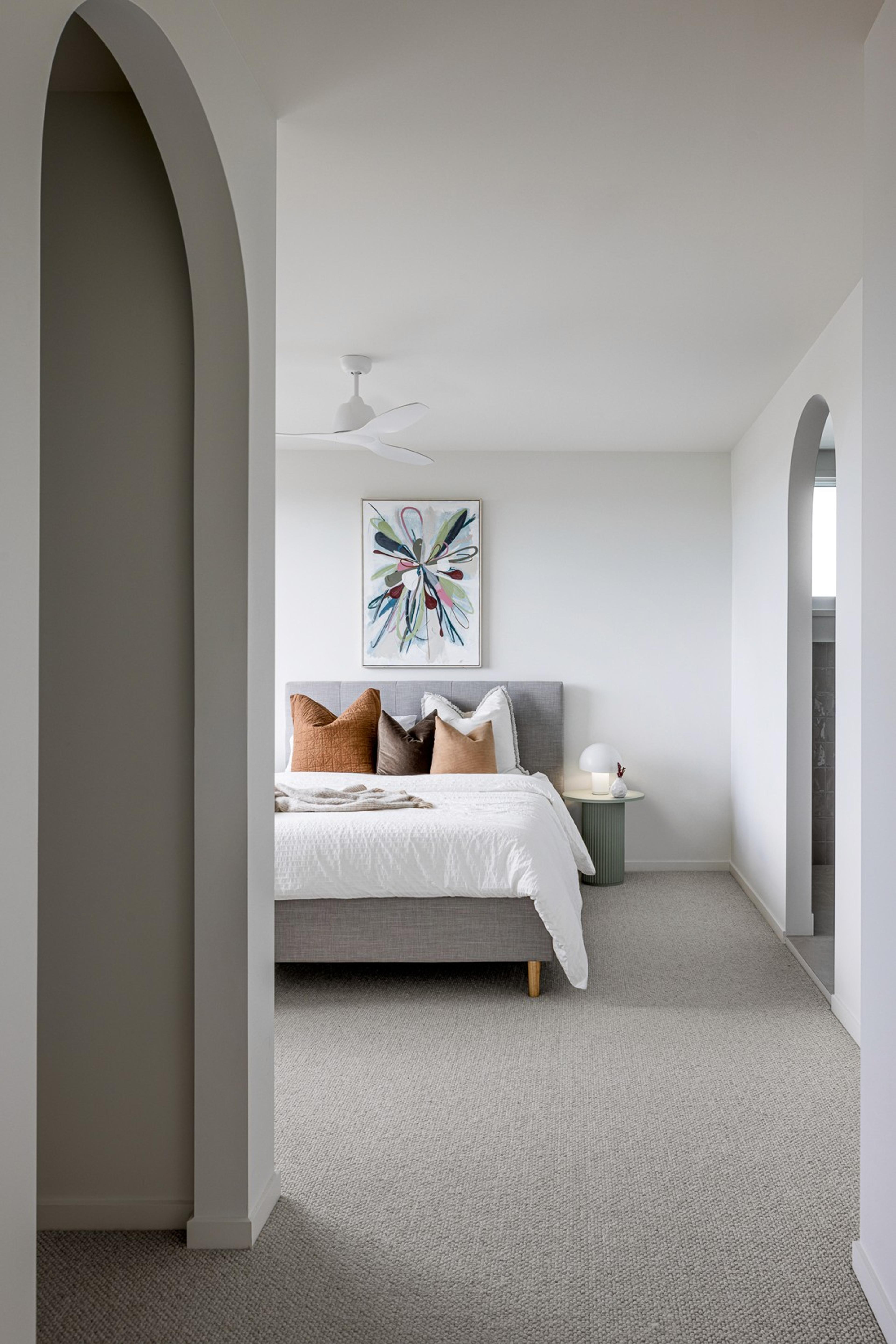 Bedroom with grey bed viewed through arched opening