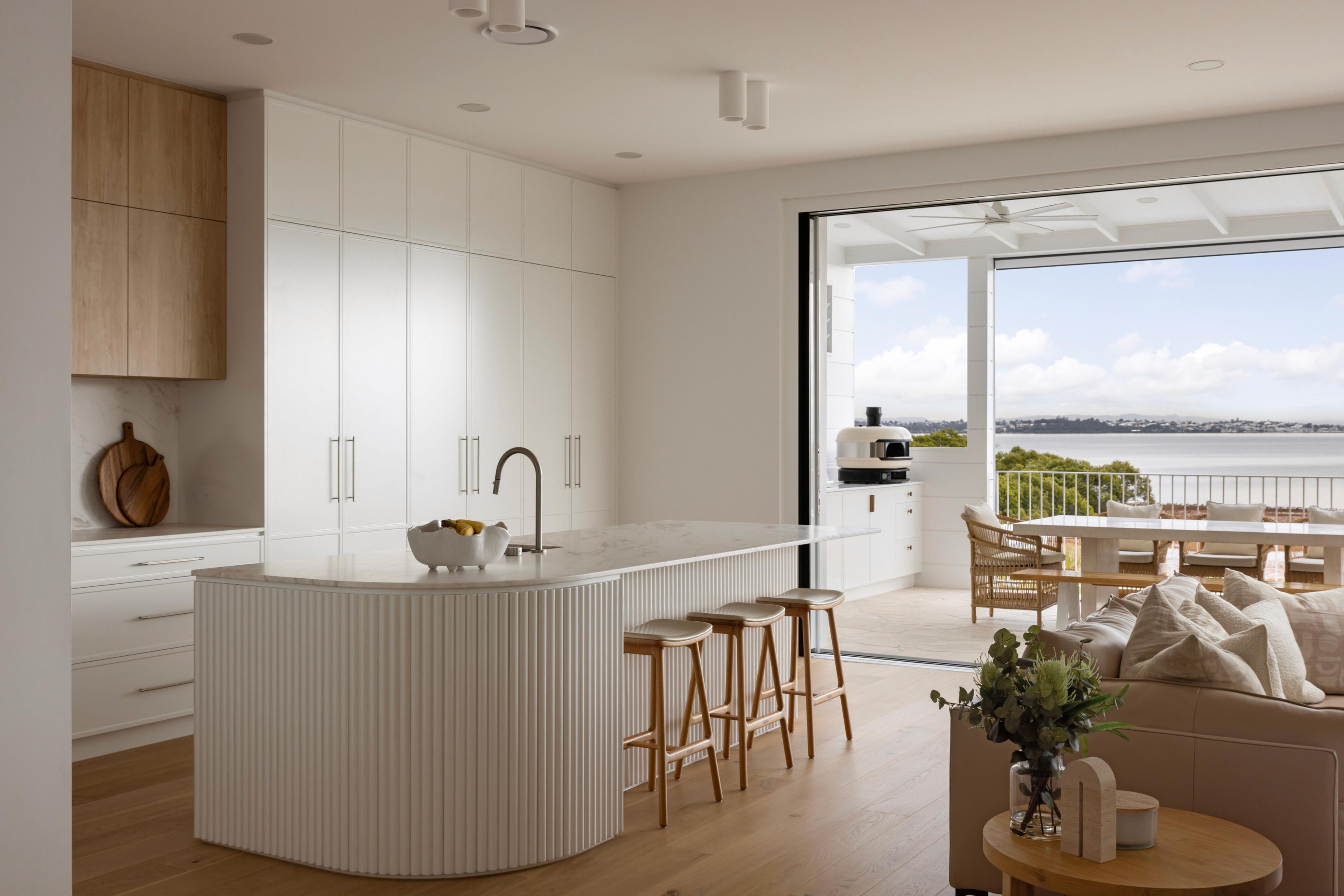 Kitchen island beside living area with bay views beyond