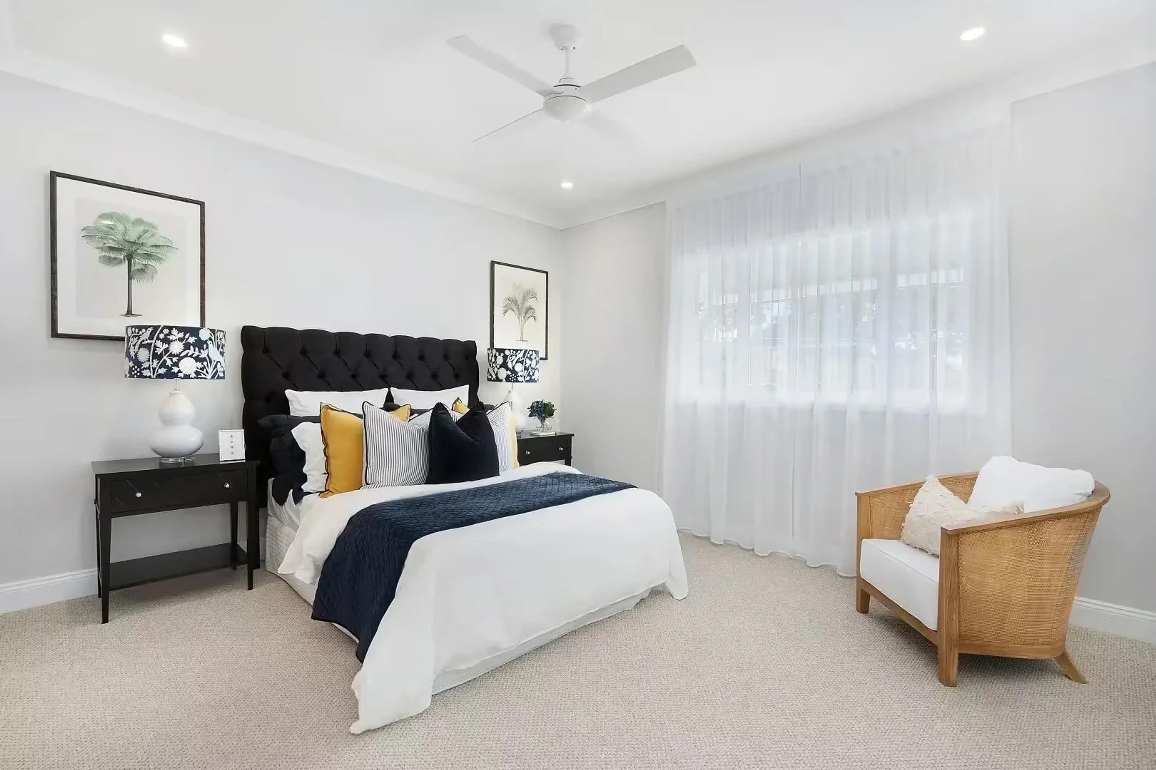 Bedroom with tufted black headboard and sheer curtains