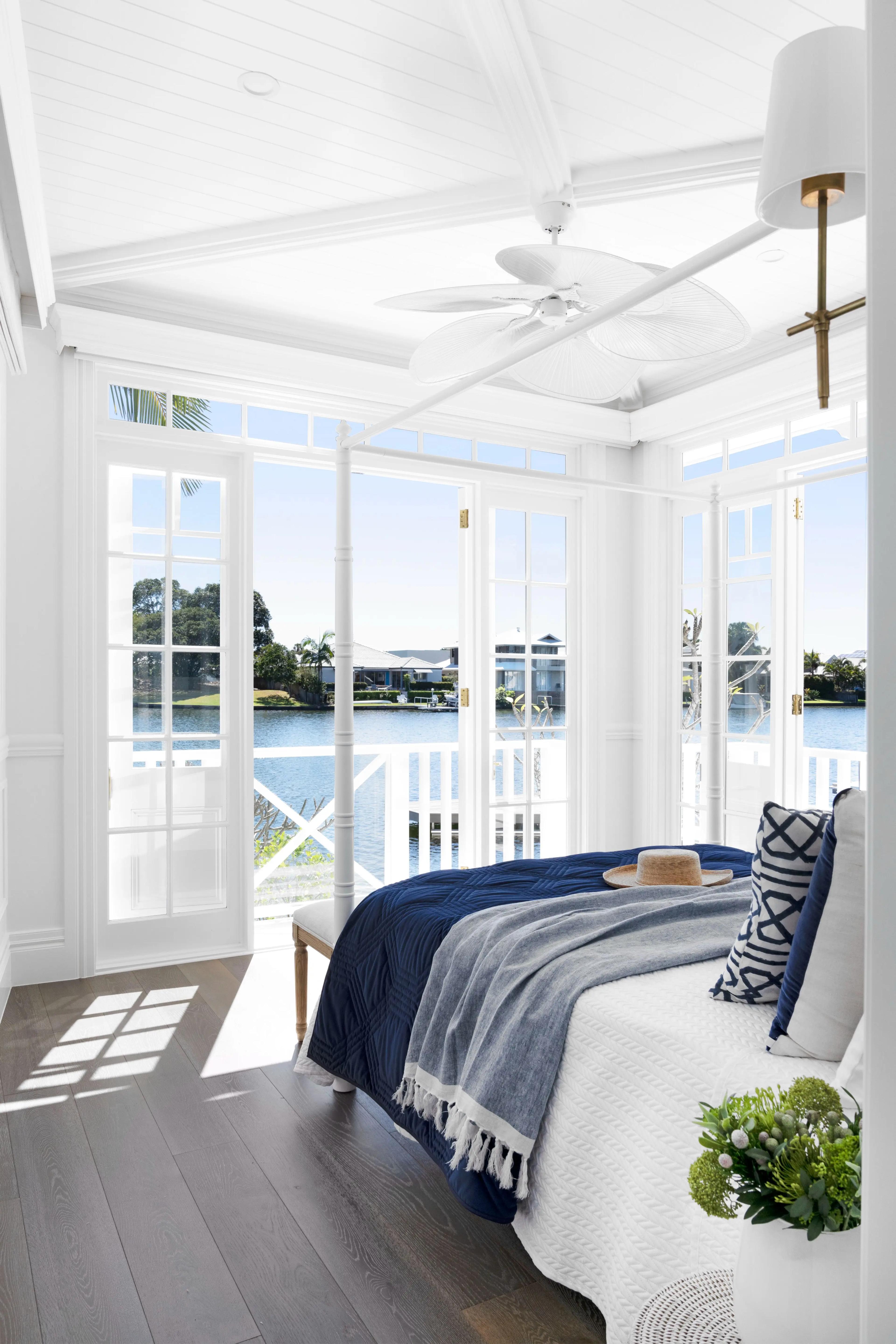 White bedroom with french doors opening to waterway views