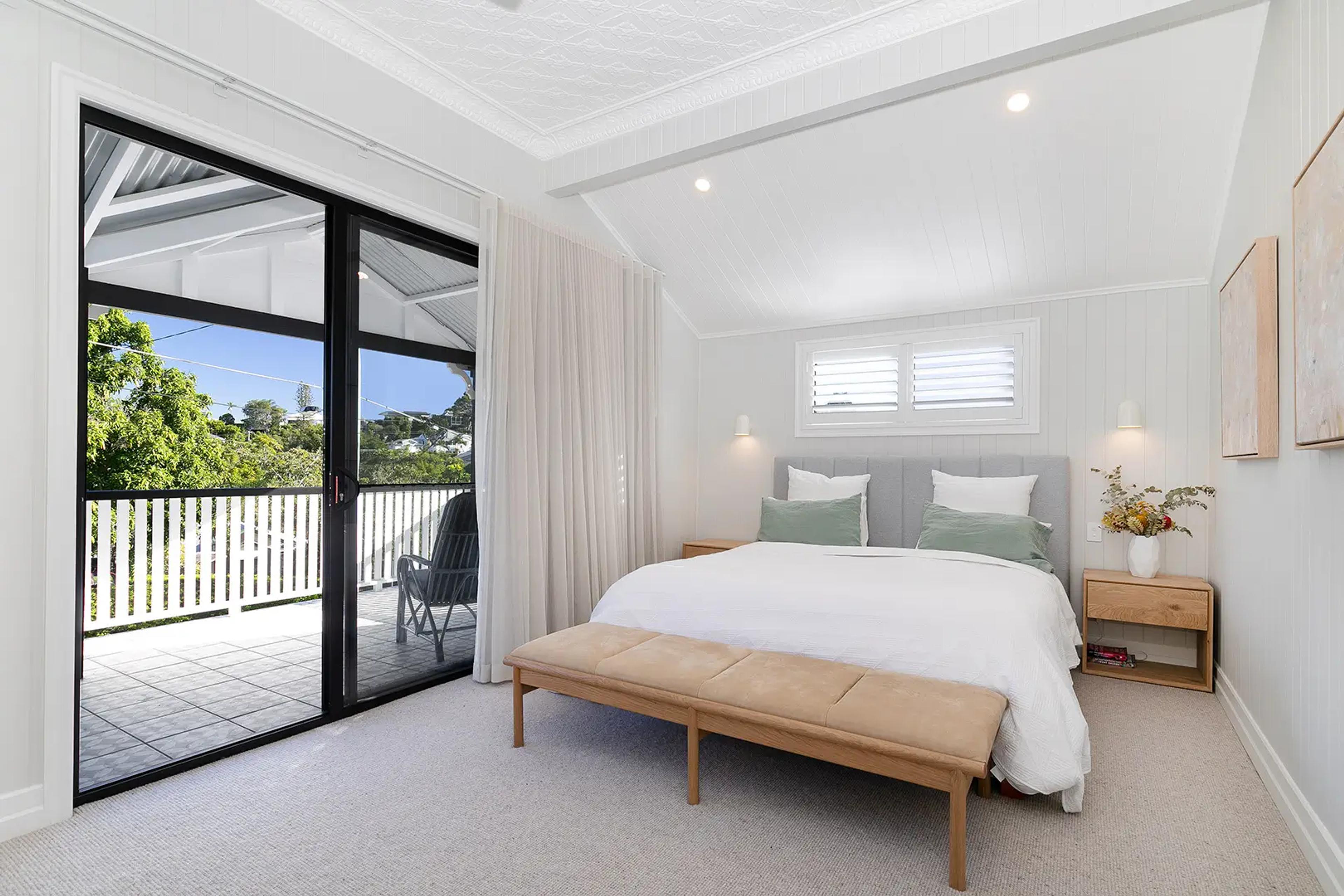 Main bedroom with door to balcony overlooking leafy suburb