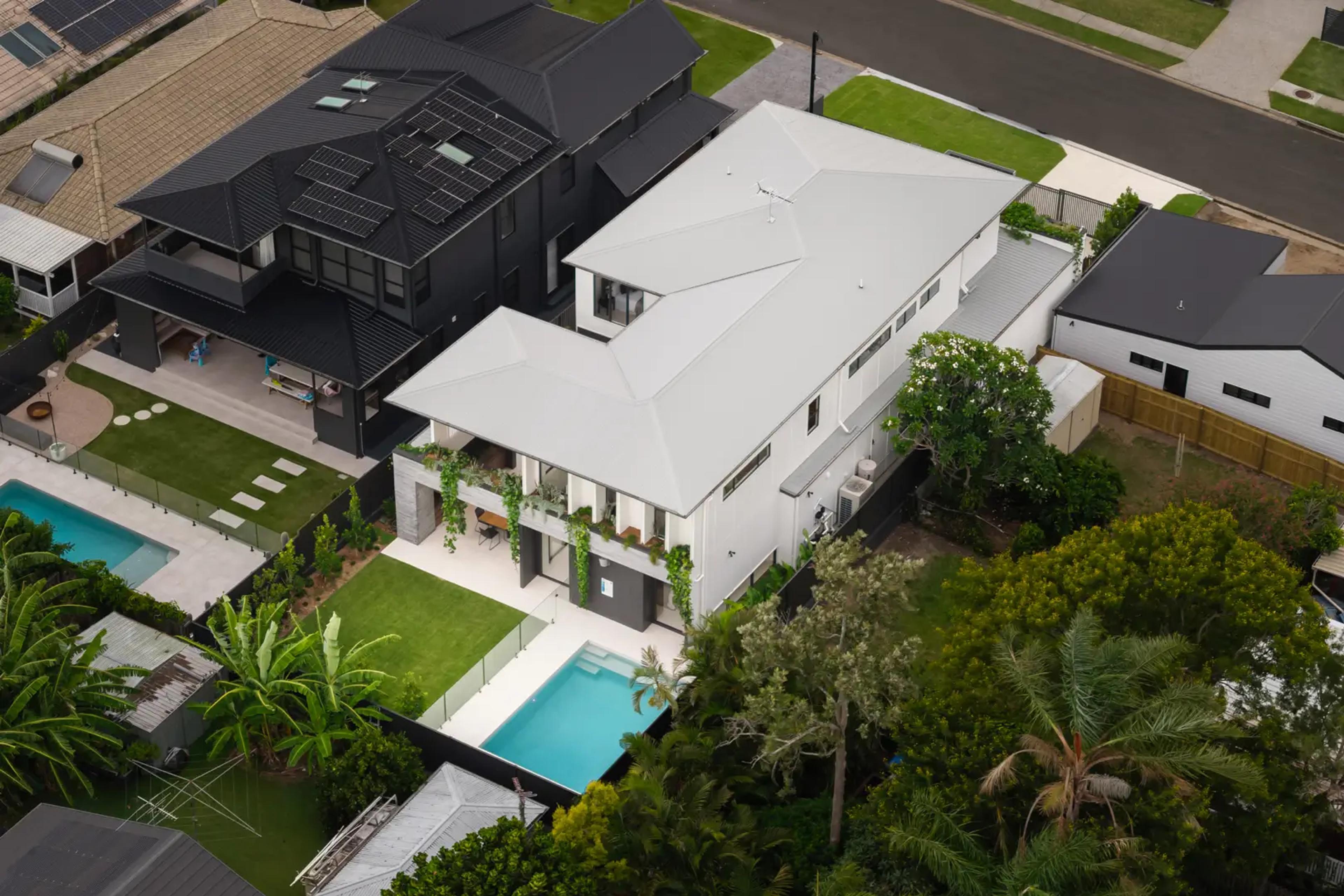 Aerial view of white roof home with pool