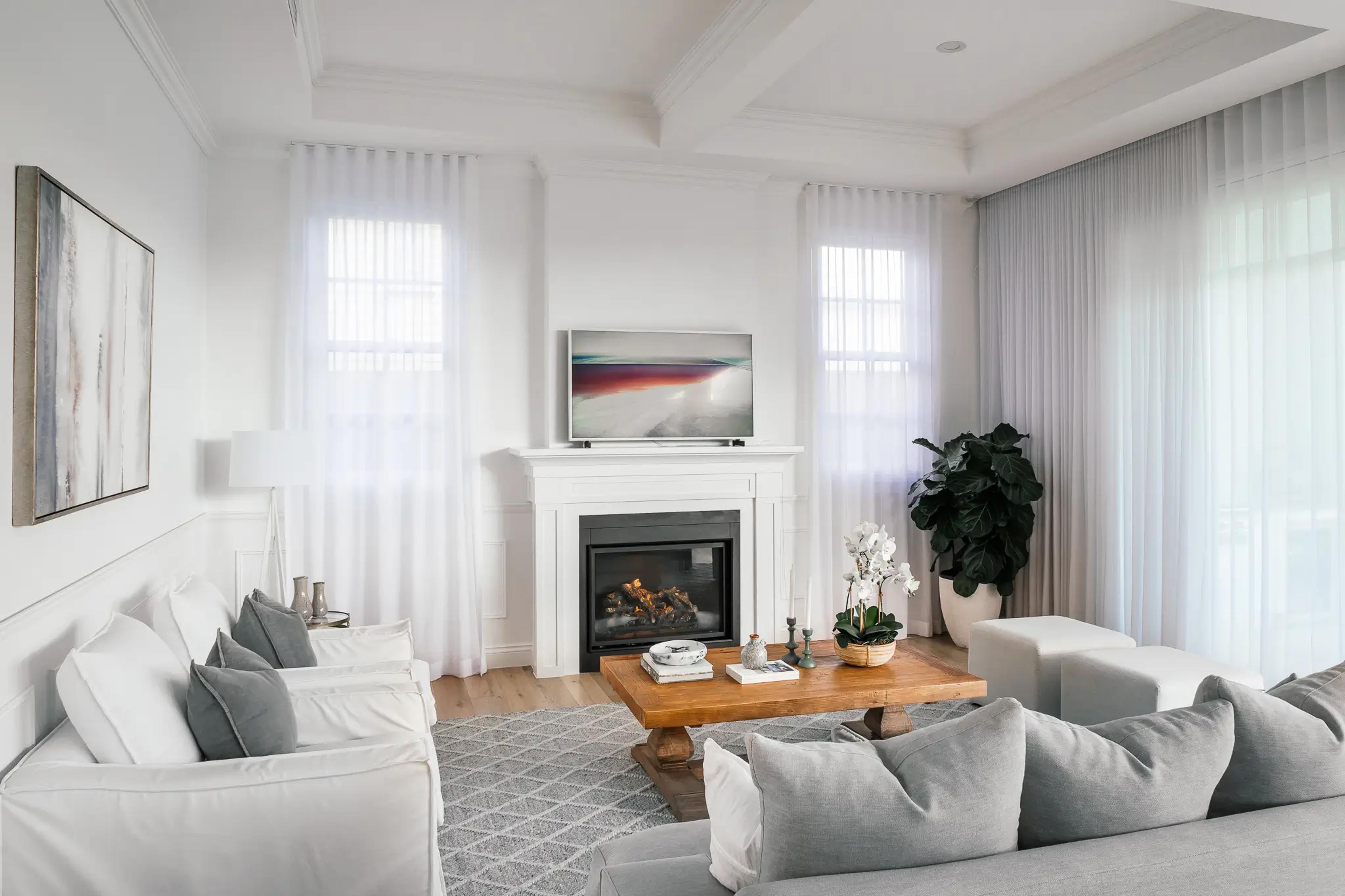 Light living room with fireplace, sheer curtains and grey sofas