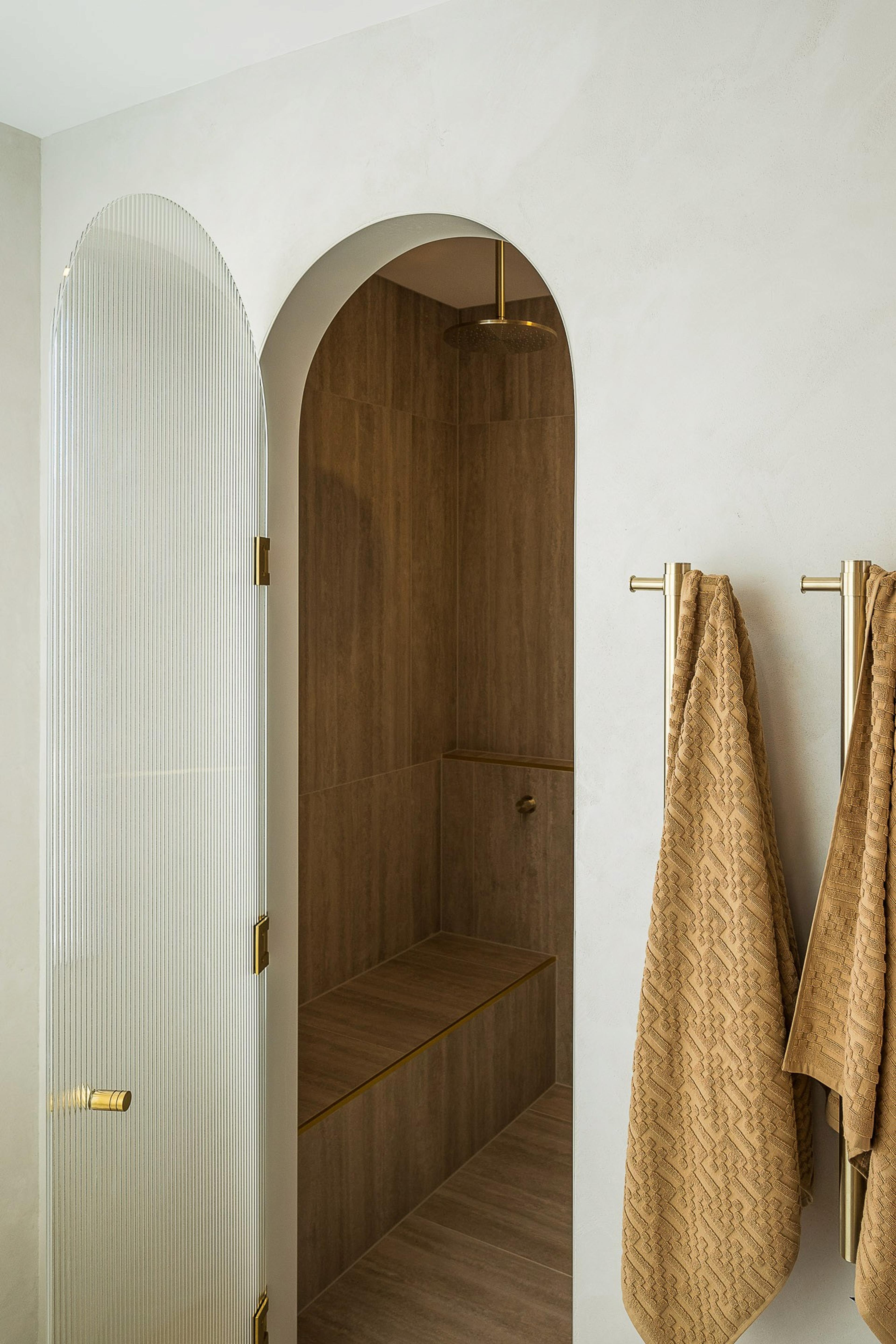 Arched shower recess with timber tiling and towels