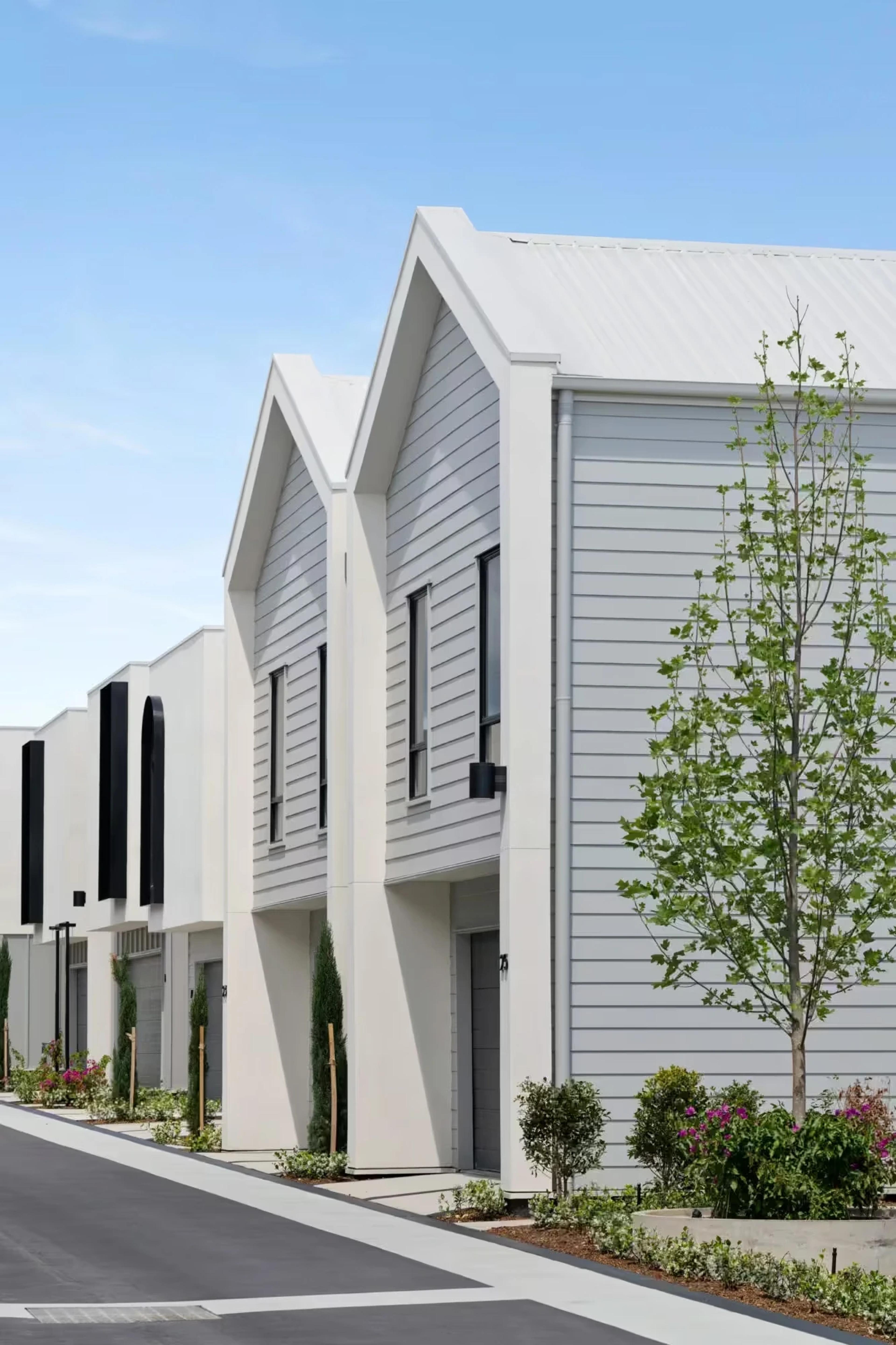Angled street view of gabled townhouses with garages