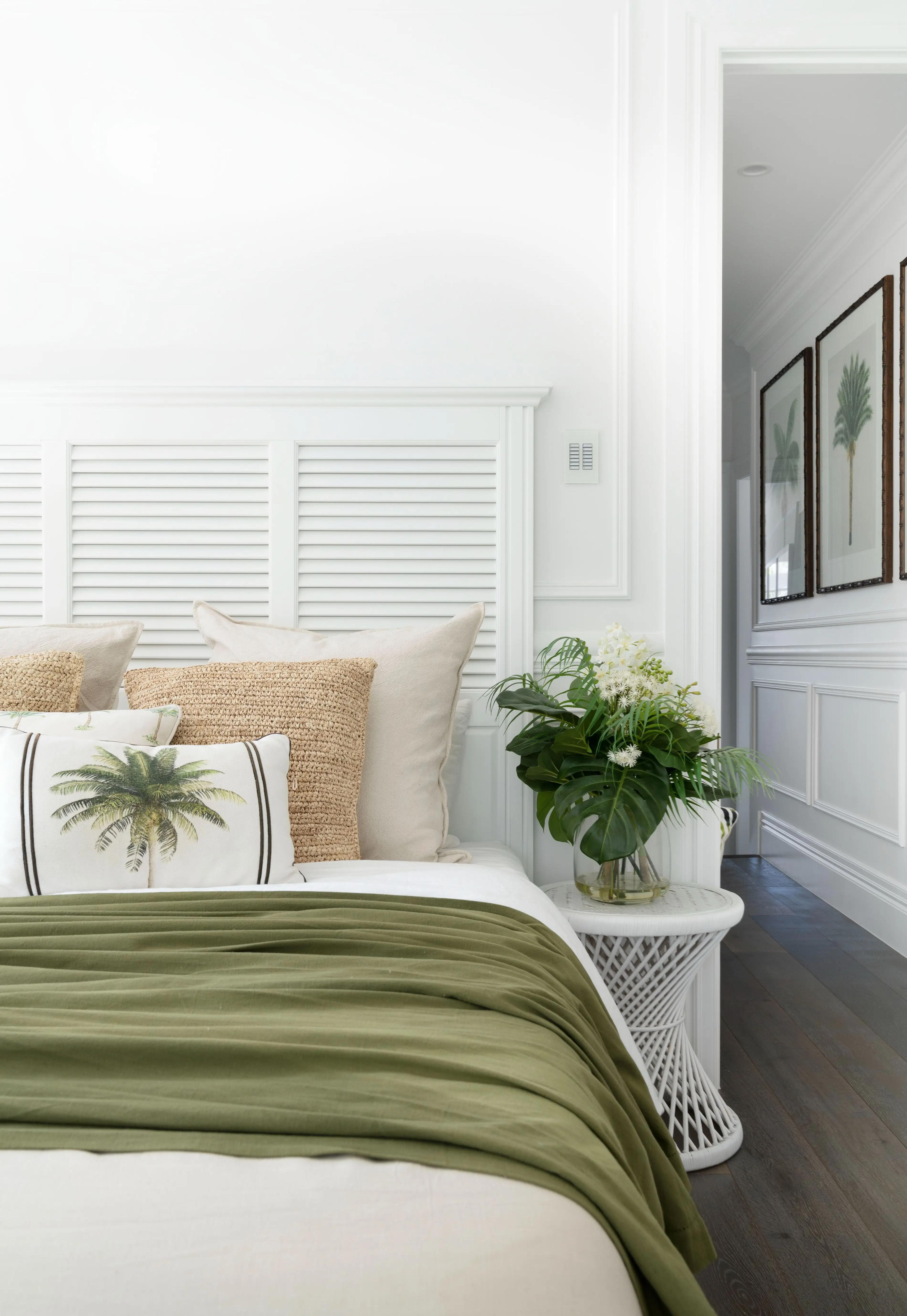 Bedside with palm print cushion and fresh greenery on white table