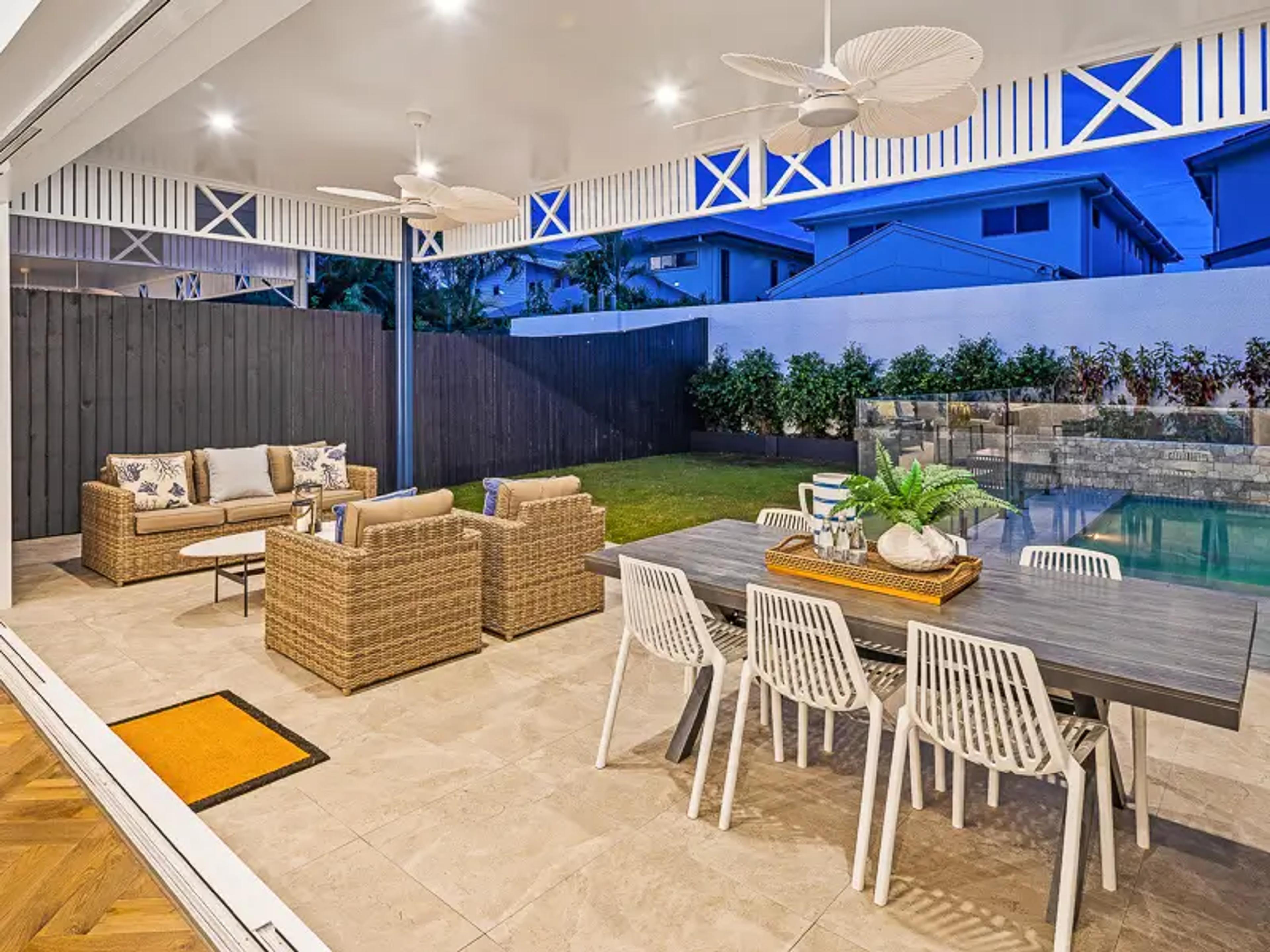 Covered alfresco lounge overlooking backyard pool and lawn