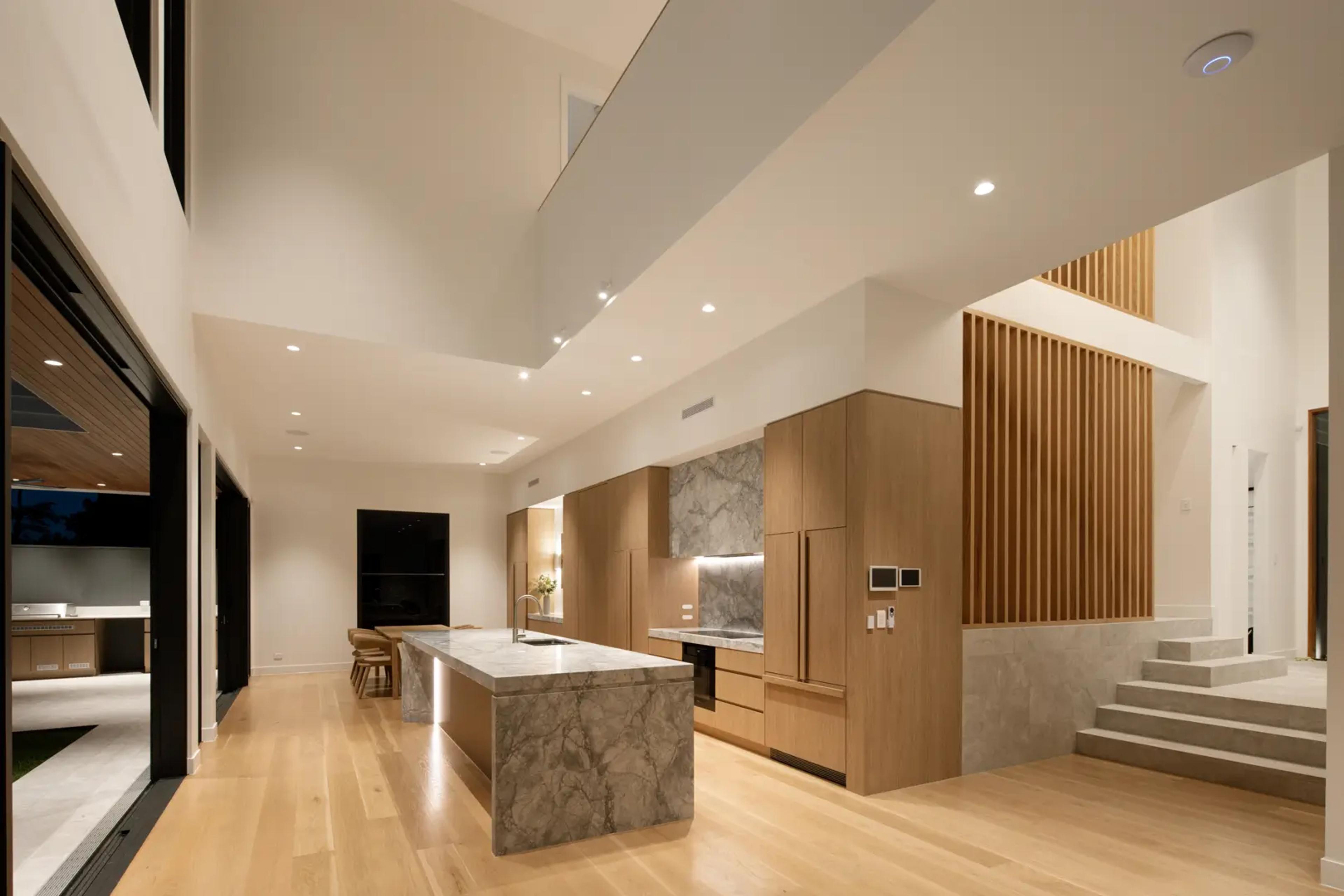 Double height kitchen with stone island and timber cabinetry