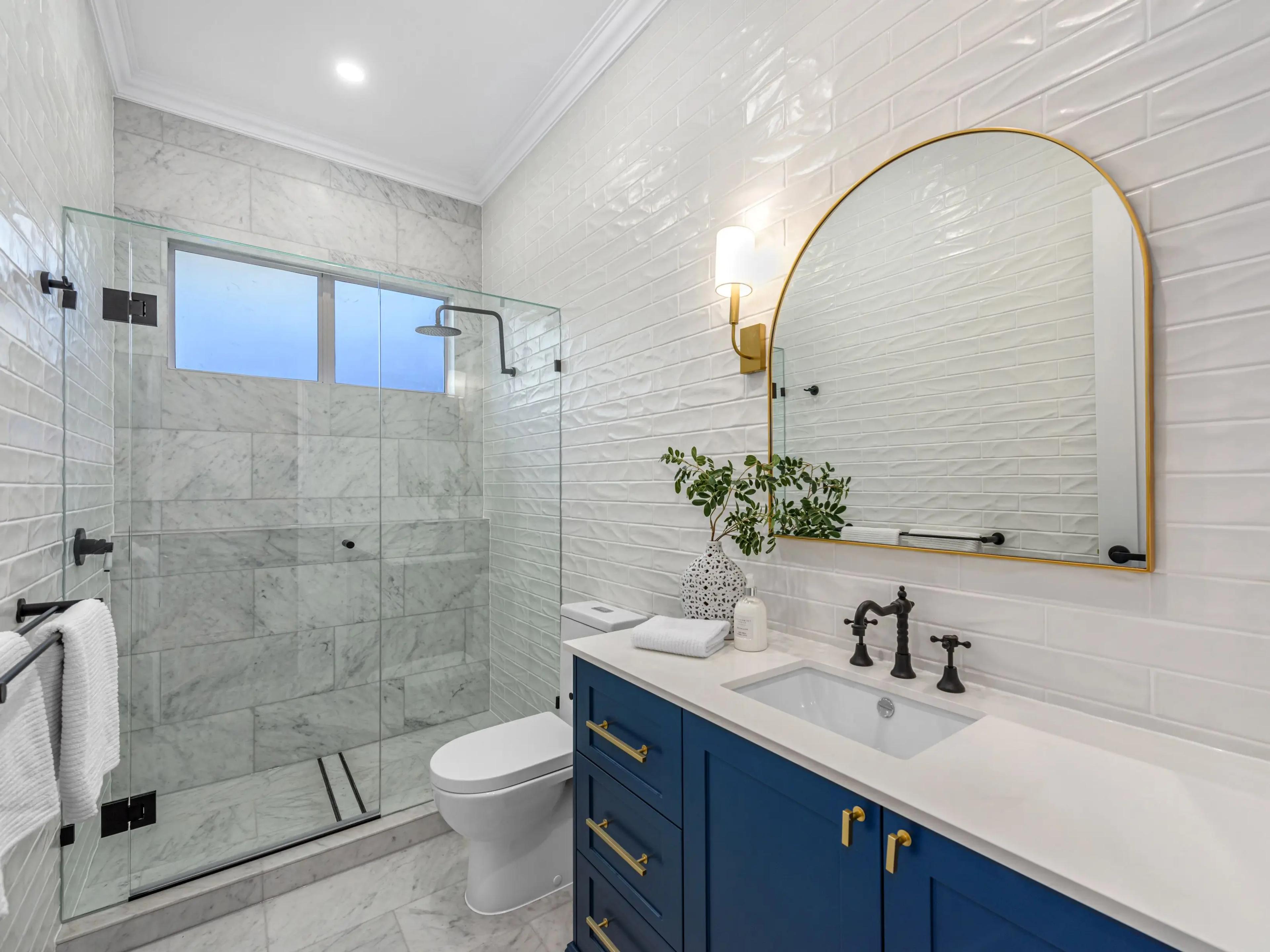 Bathroom with glass shower and arched mirror
