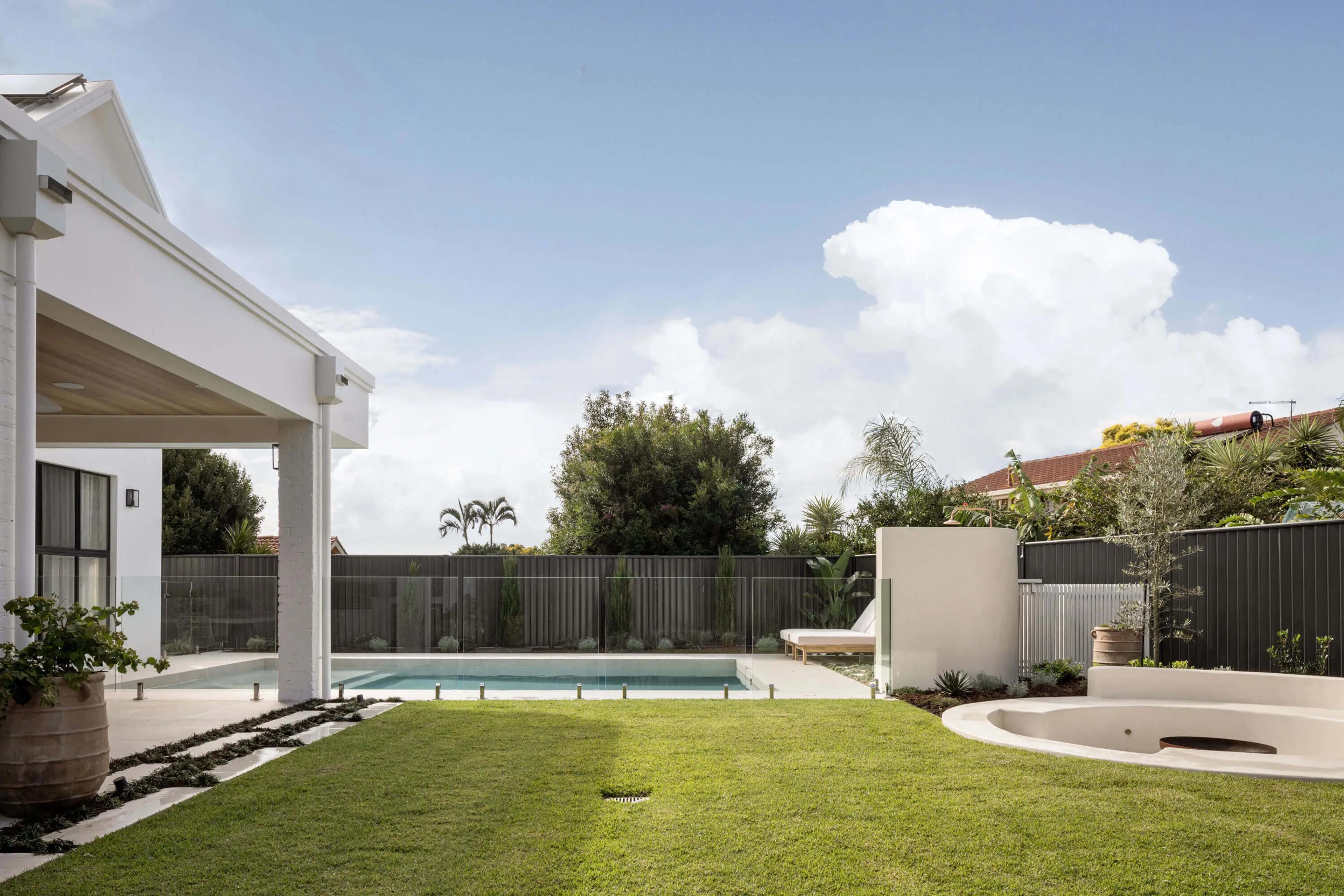 Backyard lawn and pool beside covered patio