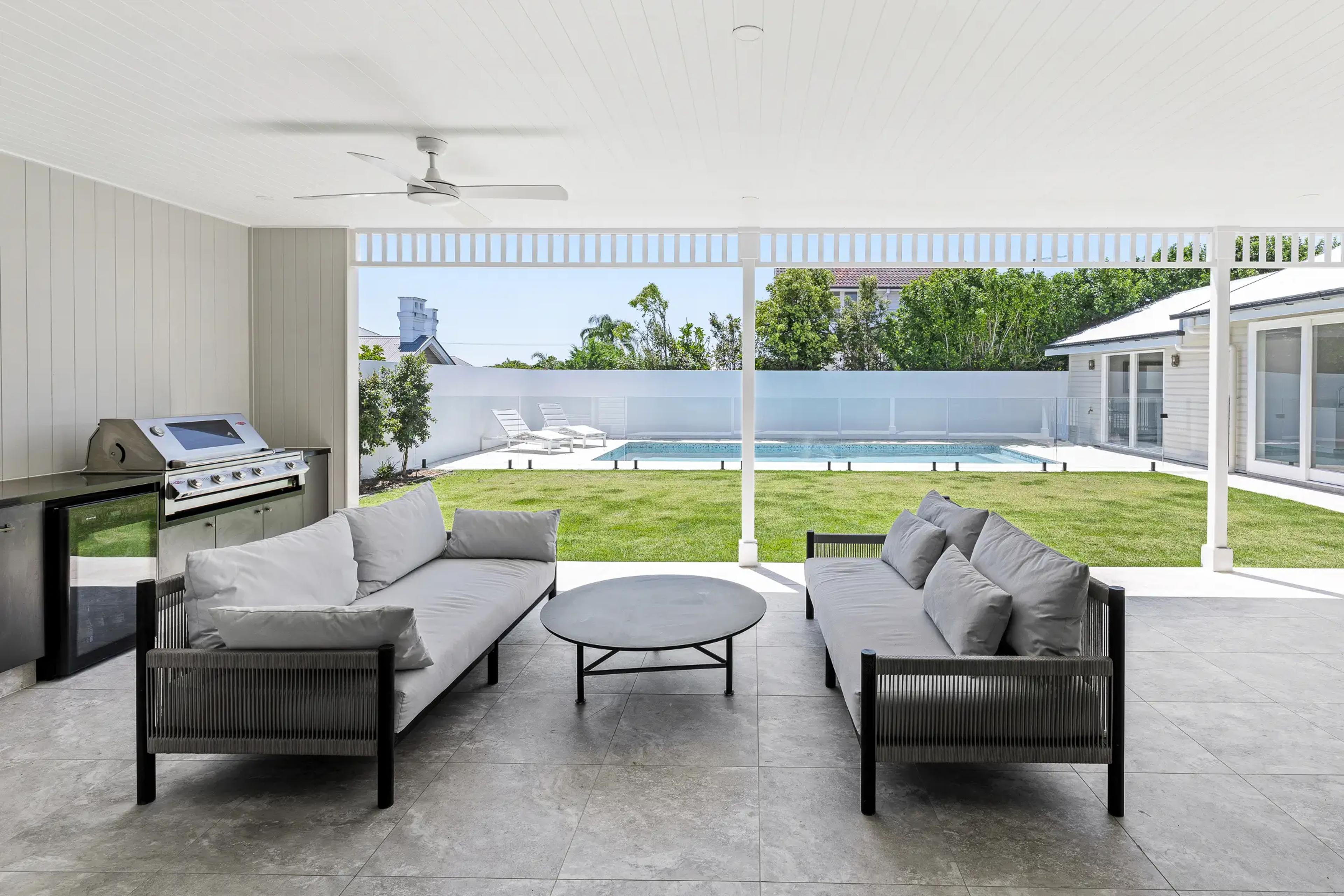 Covered outdoor lounge overlooking pool and lawn