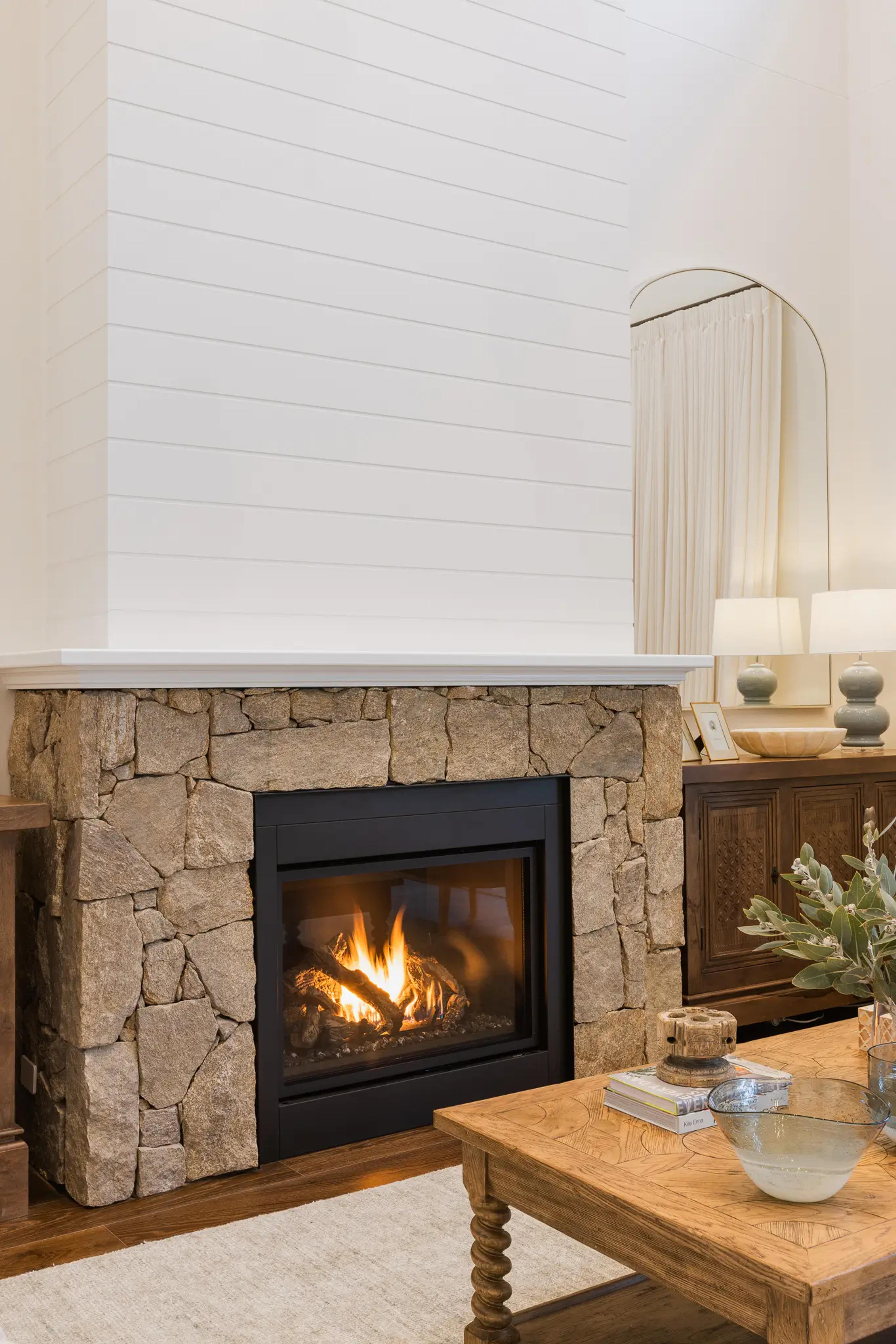 Stone clad gas fireplace with white shiplap surround and timber sideboard