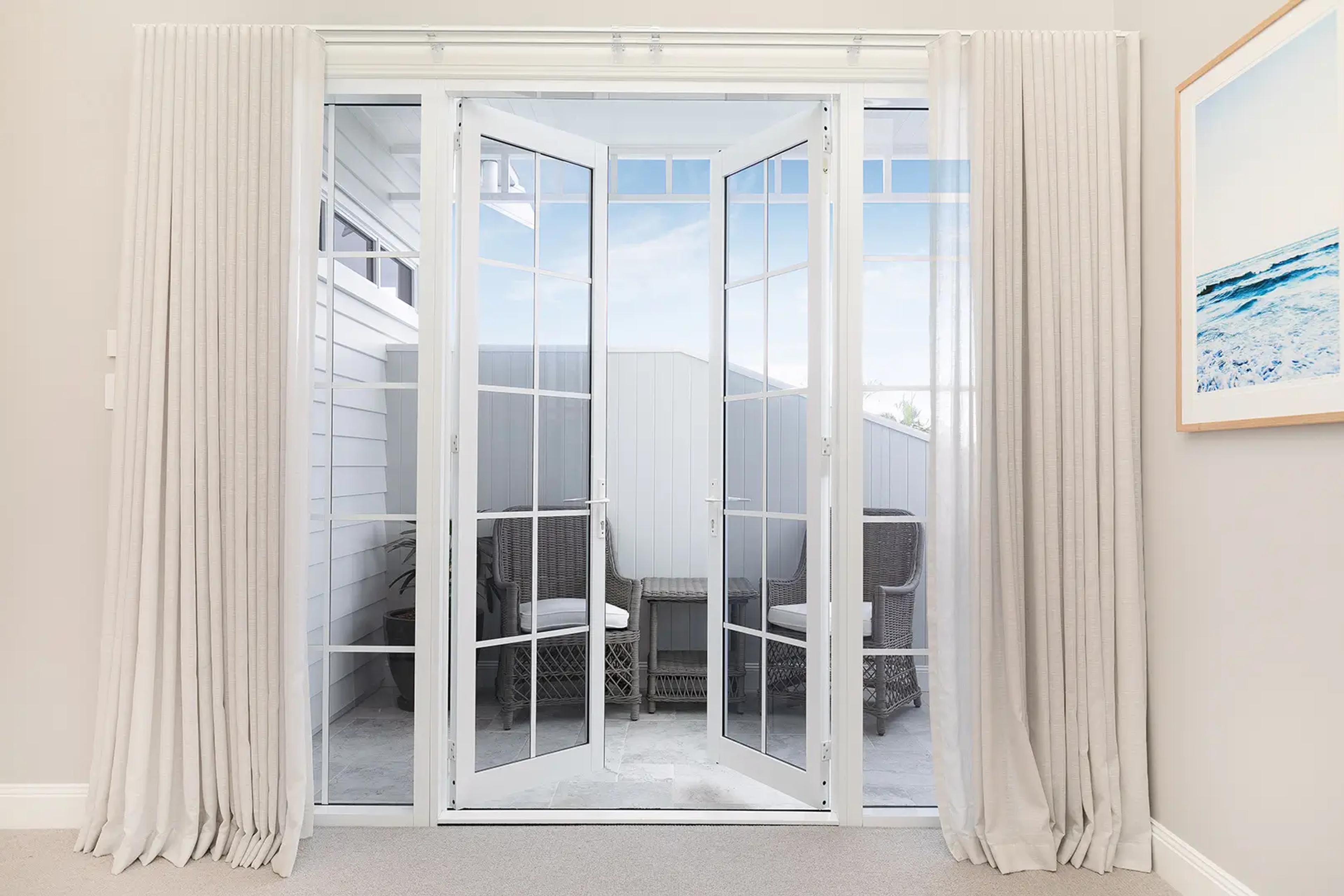 French doors with curtains leading to outdoor seating