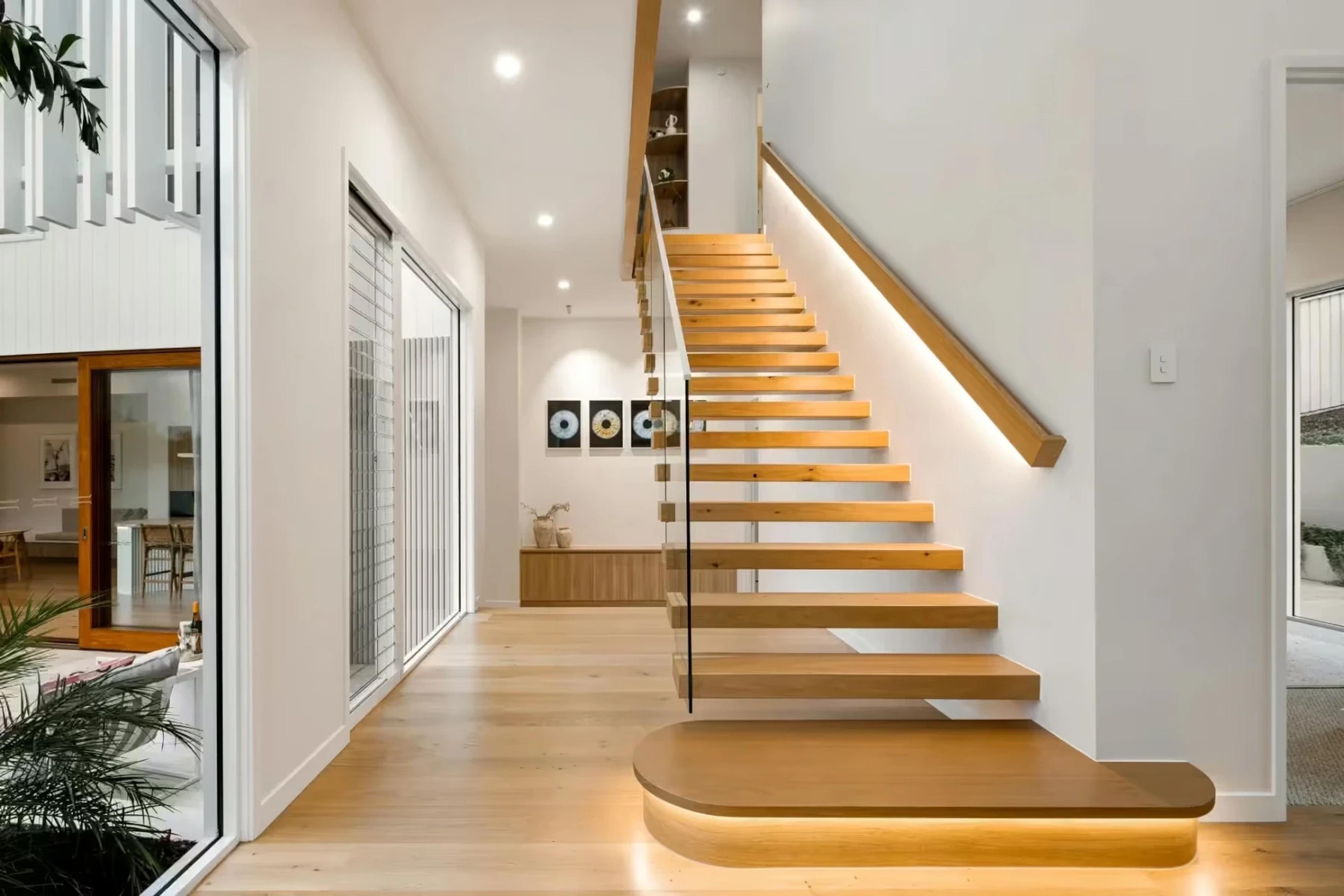 Floating timber staircase in a bright hallway with glazed wall